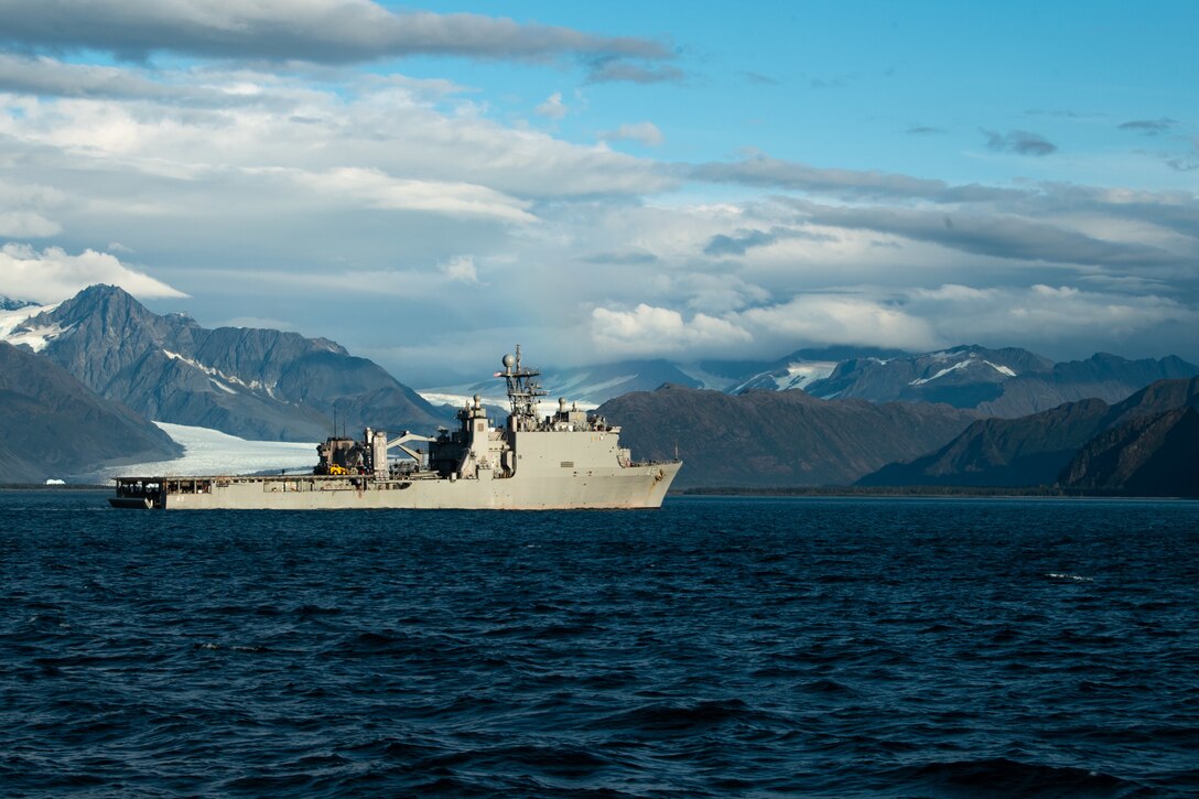 A ship transits a gulf with mountains in the background.