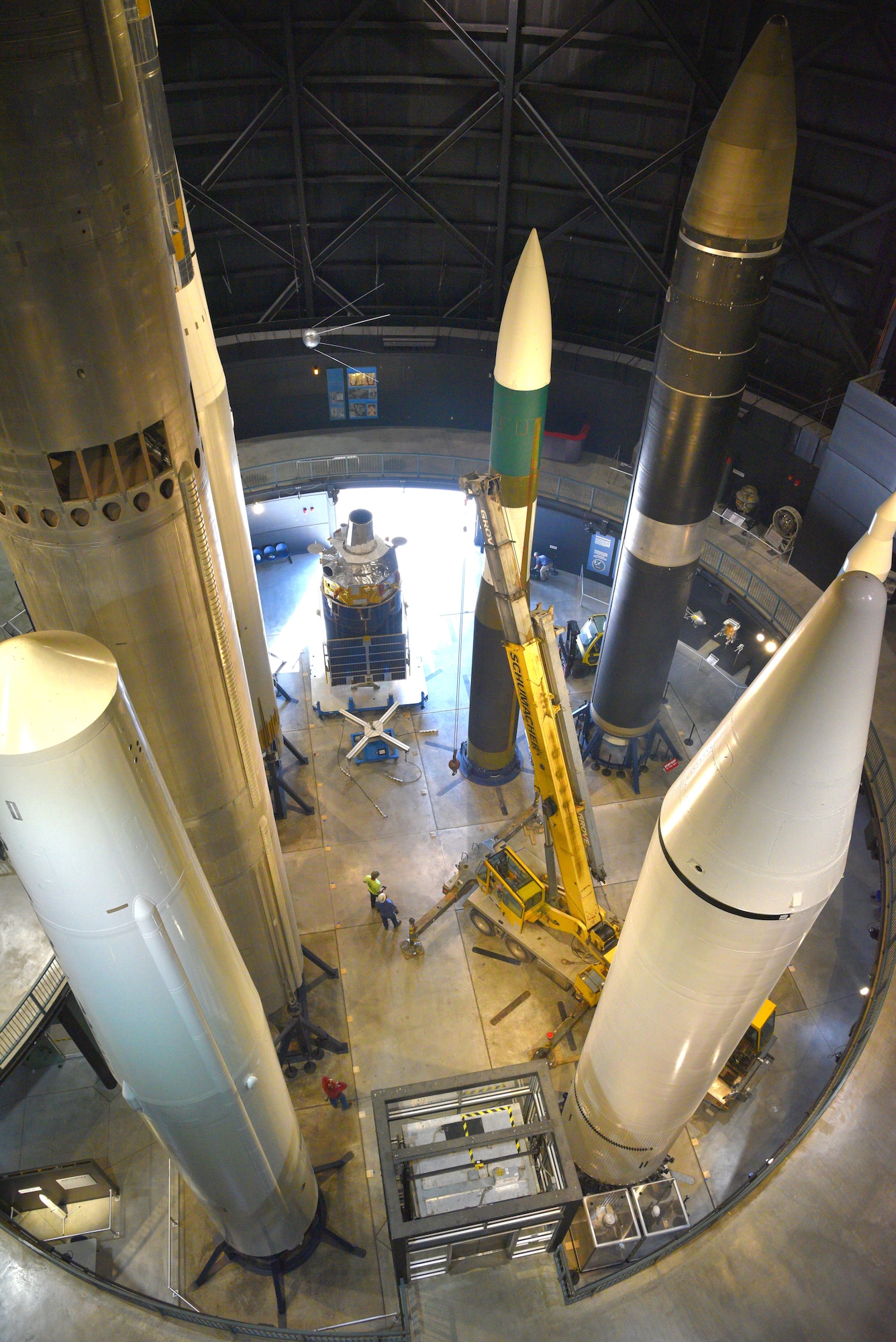 Photo of restoration crews moving a test satellite out of the missile gallery of the air force museum.