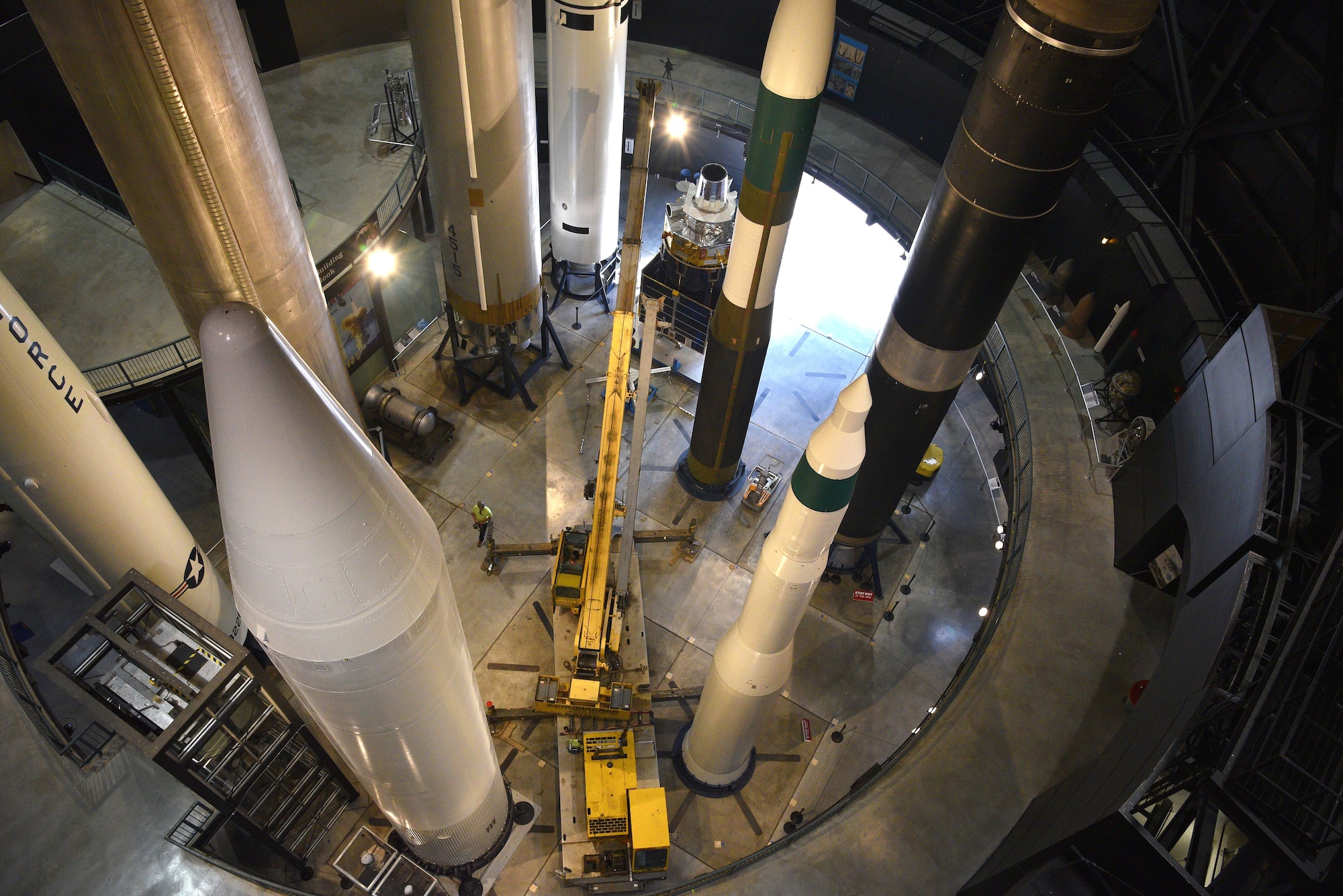 Photo of restoration crews moving a test satellite out of the missile gallery of the air force museum.