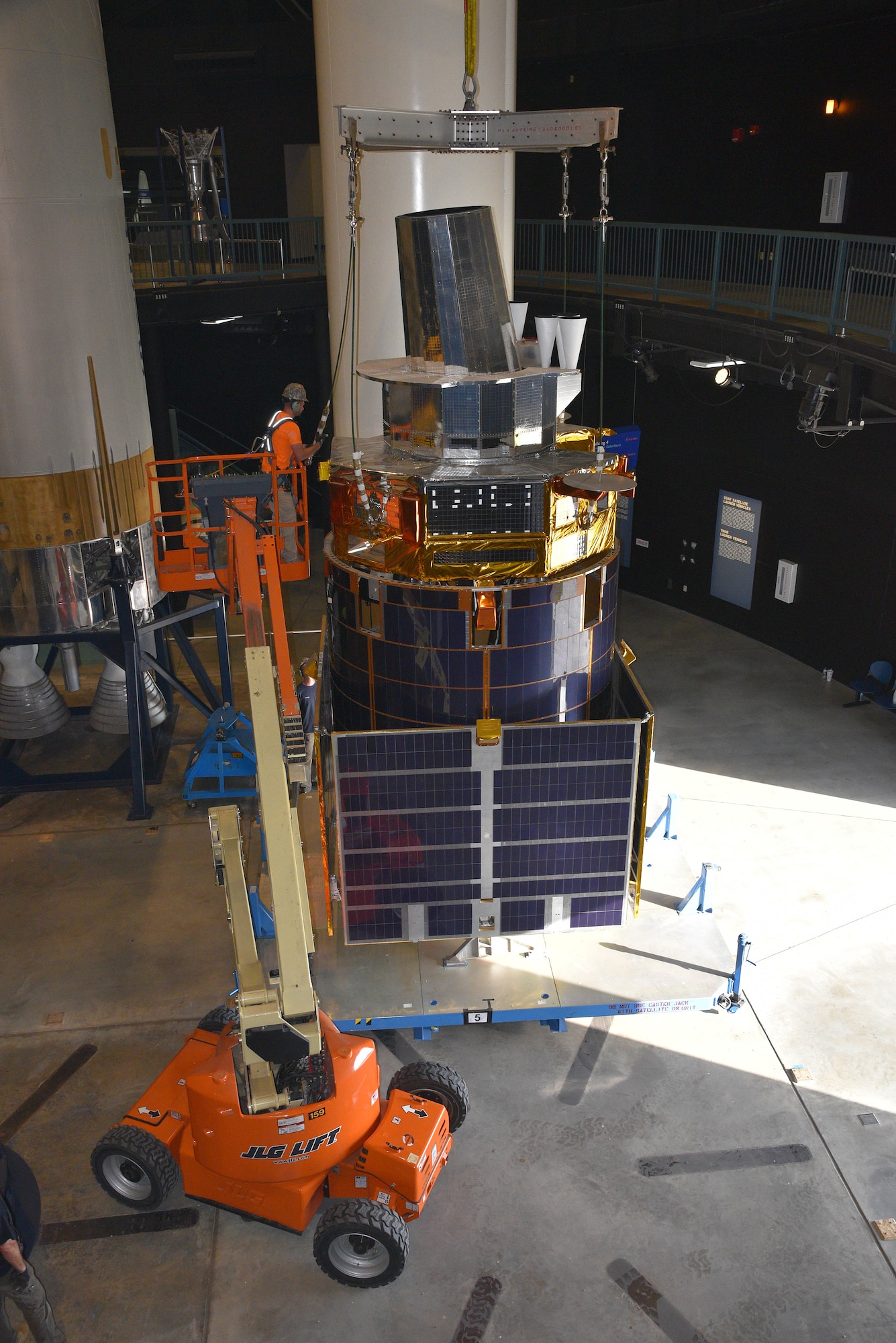 Photo of restoration crews moving a test satellite out of the missile gallery of the air force museum.