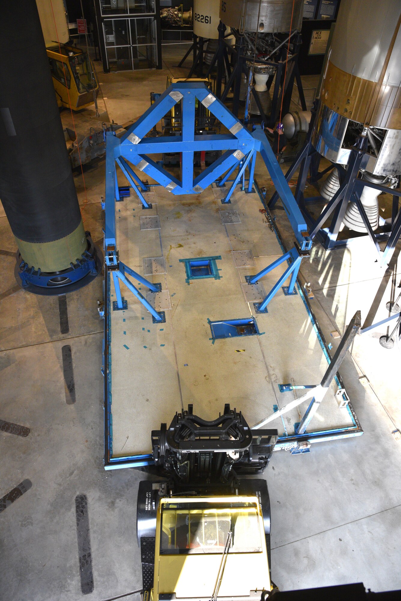 Photo of restoration crews moving a test satellite out of the missile gallery of the air force museum.