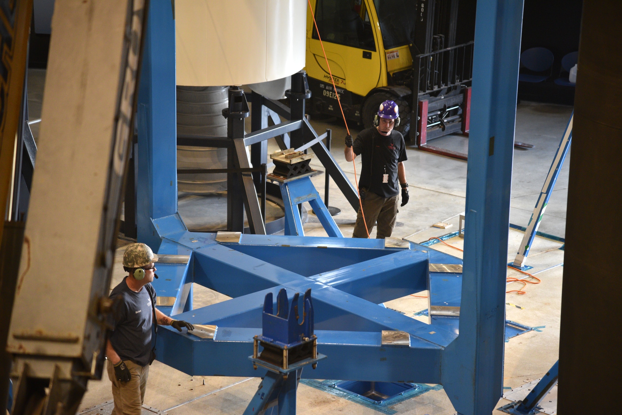 Photo of restoration crews moving a test satellite out of the missile gallery of the air force museum.