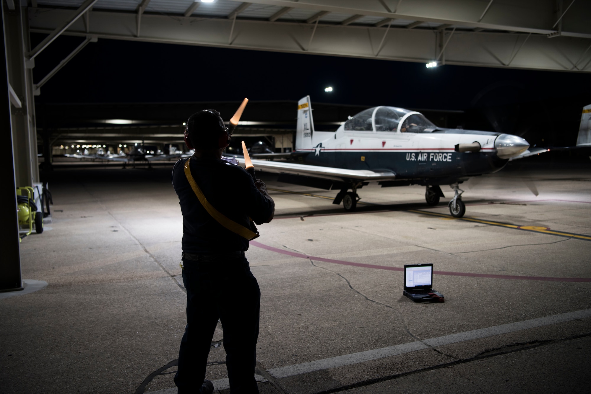 First Lt. Benjamin Peña and 1st Lt. Nicholas Myers, 85th Flying Training Squadron instructor pilots, place items inside a T-6A Texan II before takeoff on Sept. 18, 2019 at Laughlin Air Force Base, Texas. Night flying at a Specialized Undergraduate Pilot Training base allows not only more hours in the sky, but it also provides a variety experience so pilots can become accustomed to instrument flying. (U.S. Air Force photo by Senior Airman Marco A. Gomez)