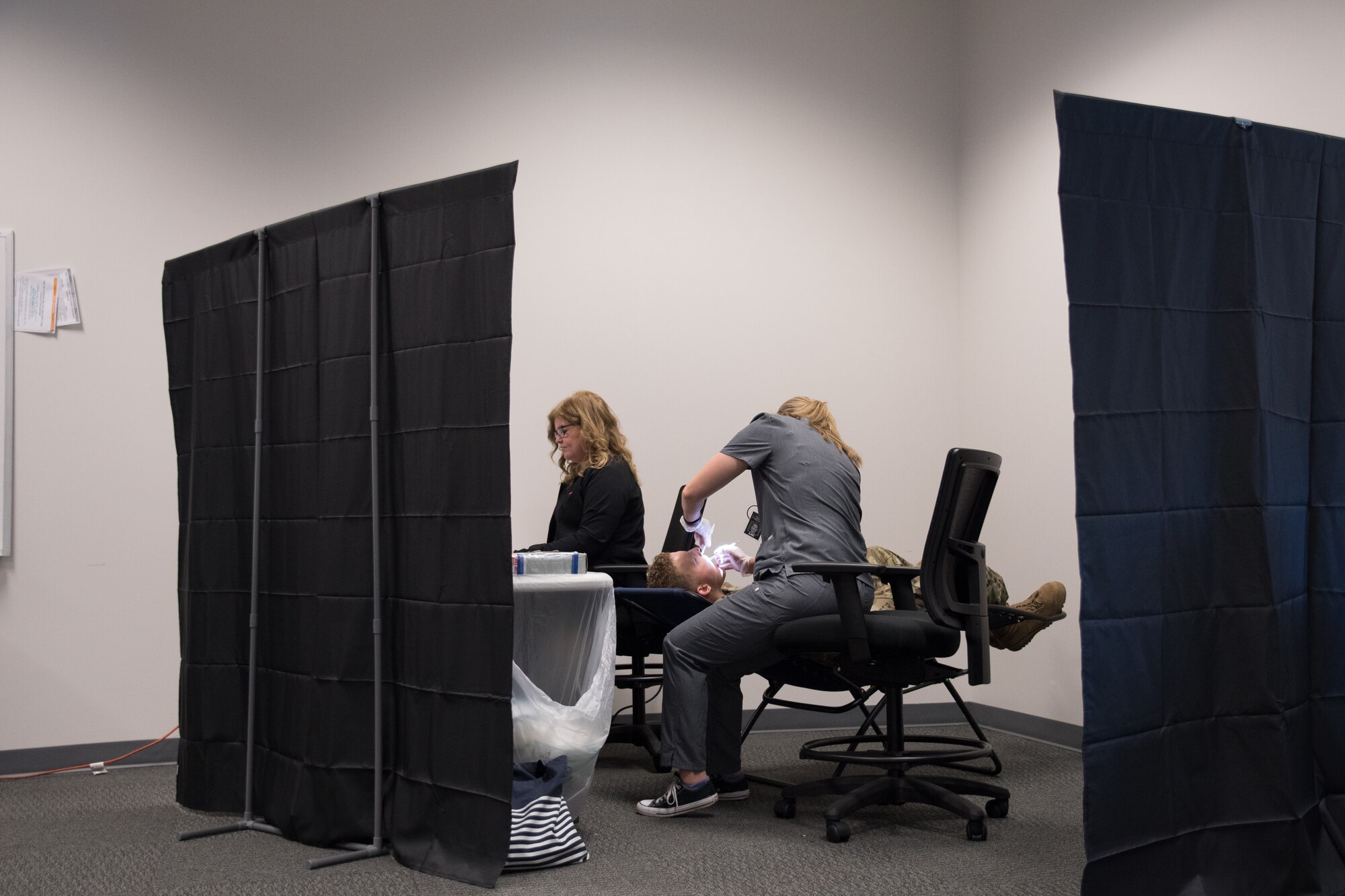 Michelle Dreyer, a dental assistant, left, and Dr. Kinsey Walters, DDS, perform a dental screening in a mobile setup at Whiteman Air Force Base, Mo., Sept. 15, 2019. The team is able to meet with up to 25 patients per hour. (U.S. Air Force photo by Staff Sgt. Missy Sterling)