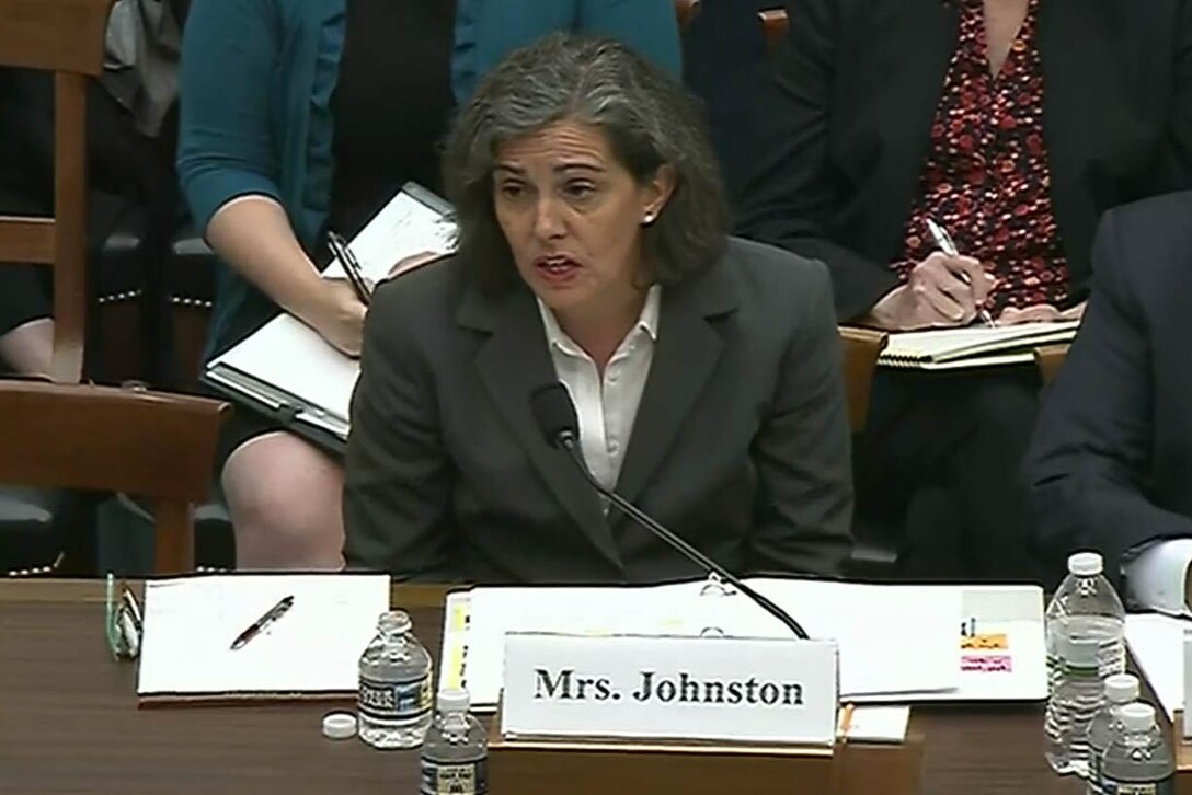 Woman dressed in a dark suit speaks at a hearing.