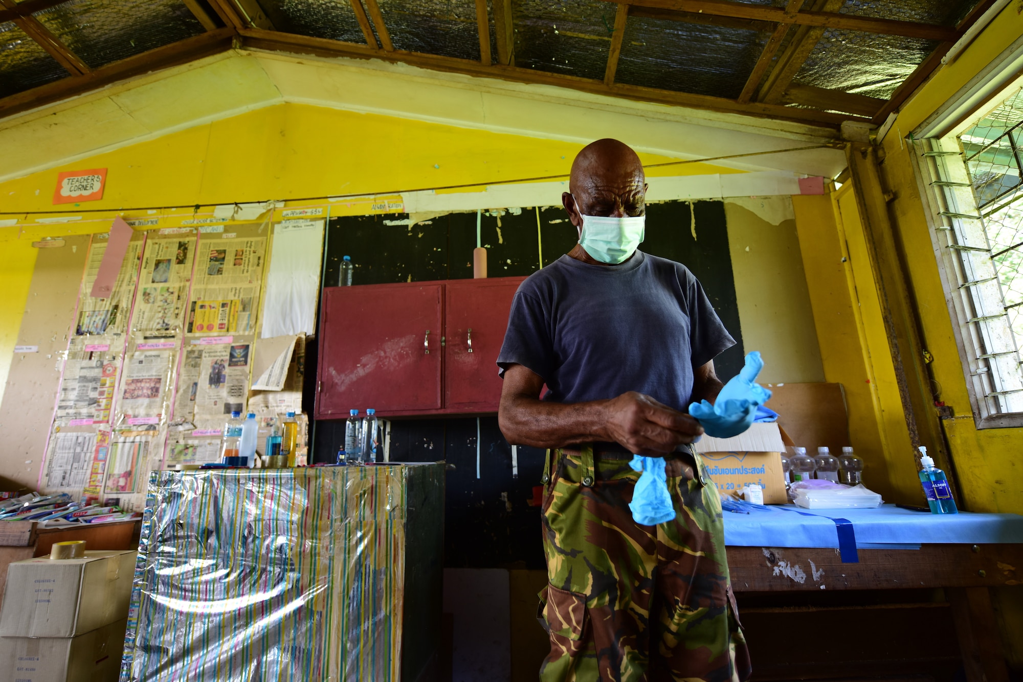 Papua New Guinea Defence Force Maj. Bais Gwale, a Pacific Angel 19-4 dentist, puts gloves on prior to treating a patient at a health services outreach site in Lae, Papua New Guinea Sept. 9, 2019. Bais has been a practicing dentist, teacher and mentor for nearly five decades in the Papua New Guinea government and the local defence force. (U.S. Air Force photo by Tech. Sgt. Jerilyn Quintanilla)