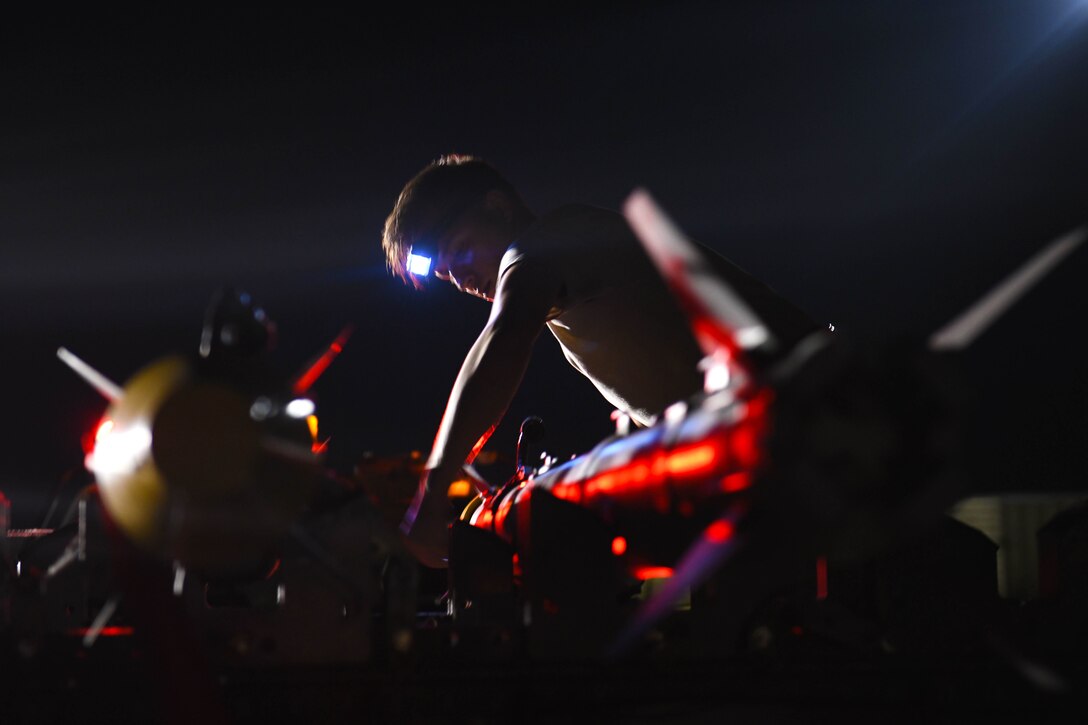 An airman examines missiles at night.