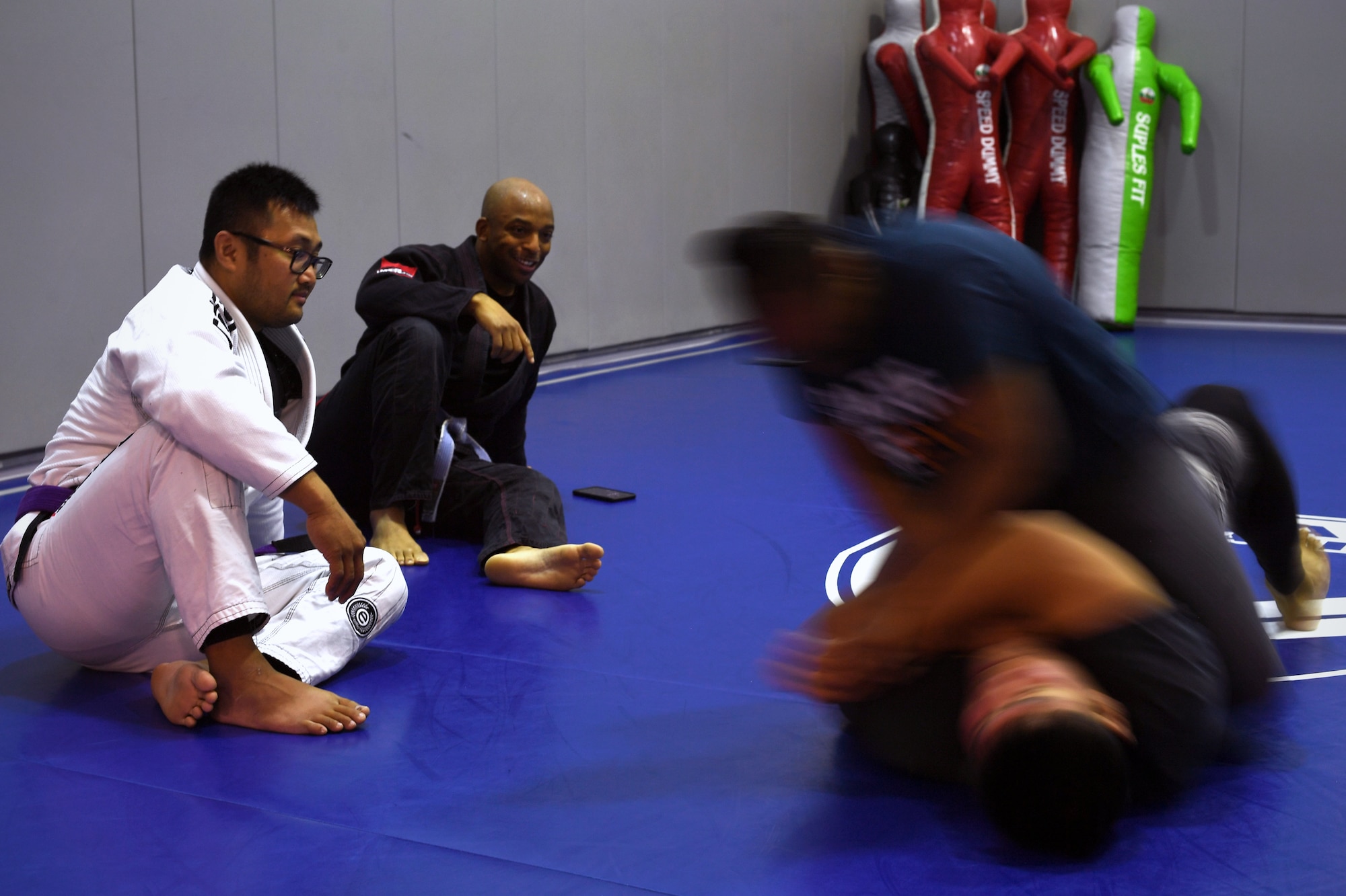 Tech. Sgt. Darwin Valencia, 319th Logistics Readiness Squadron travel management office section chief, far left, and Tech. Sgt. John Squire, 319th Healthcare Operational Squadron mental health flight chief, center, provide form tips to a set of grappling partners during a resiliency event Sept. 17, 2019, on Grand Forks Air Force Base, North Dakota. Squire organized and hosted “Grappling with Adversity,” which was an opportunity for members of the base to learn the basics of Jiu Jitsu and apply its diligence to their mental health and resilience. (U.S. Air Force photo by Senior Airman Elora J. Martinez)