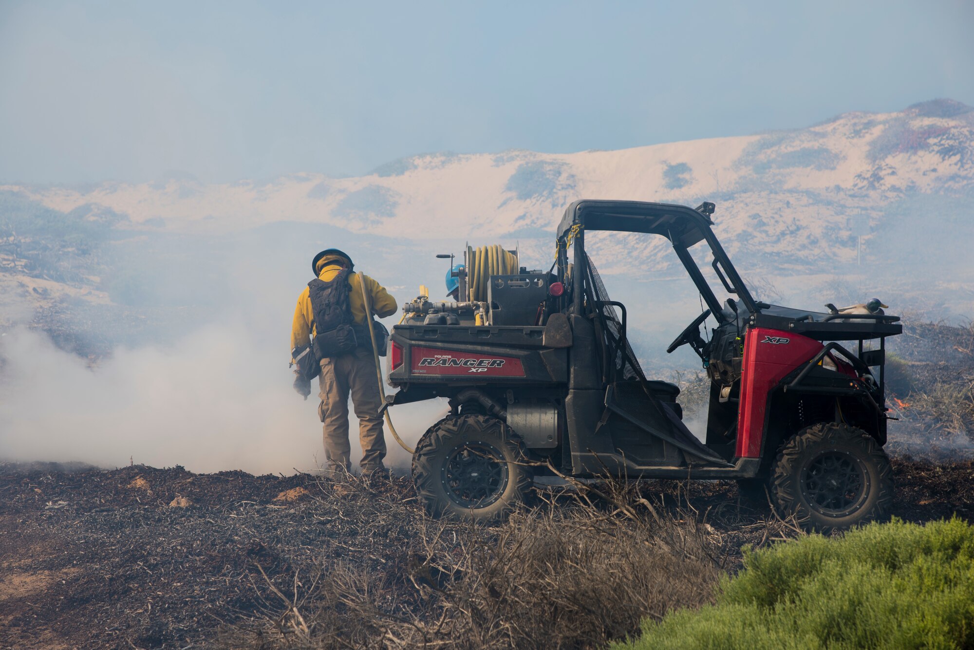 A member of Vandenberg Hotshots closes in on a controlled fire Sept. 18, 2019 at Vandenberg Air Force Base, Calif. A team of 18 Hotshots worked on the controlled burn of grassland and coastal sage at Purisma Point Beach. The goal of this one-day burn was to increase the habitat for the Western Snowy Plover by re-contouring the sand dunes for more suitable nesting conditions while also reducing the risk of wildfire. (U.S. Air Force photo by Airman 1st Class Aubree Milks)