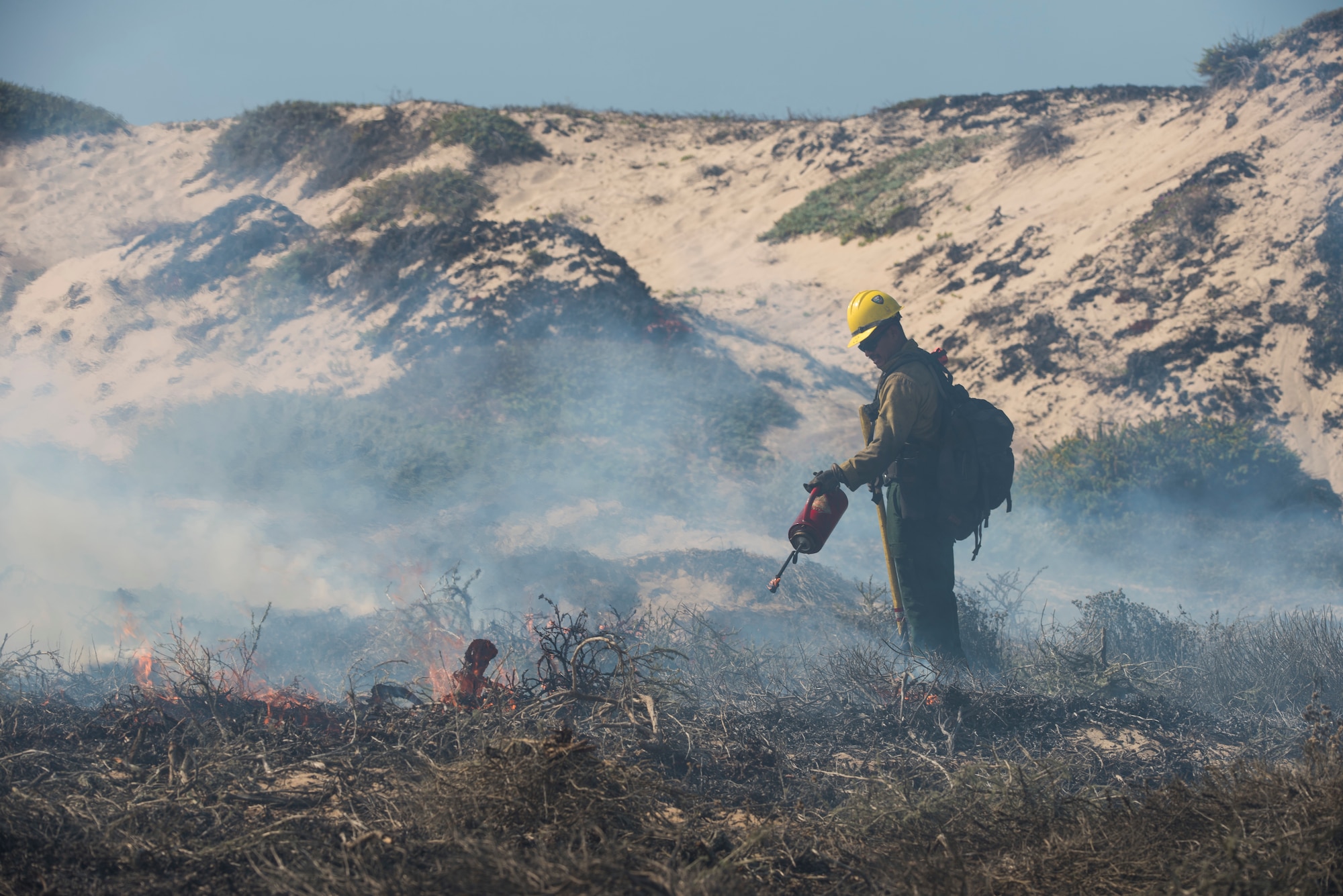 A member of Vandenberg Hotshots subdues a controlled fire Sept. 18, 2019 at Vandenberg Air Force Base, Calif. The goal of this one-day burn was to reduce the risk of wildfires, as well as increase the habitat for an endangered species that resides in the area by re-contouring the sand dunes for more suitable nesting conditions. (U.S. Air Force photo by Airman 1st Class Aubree Milks)