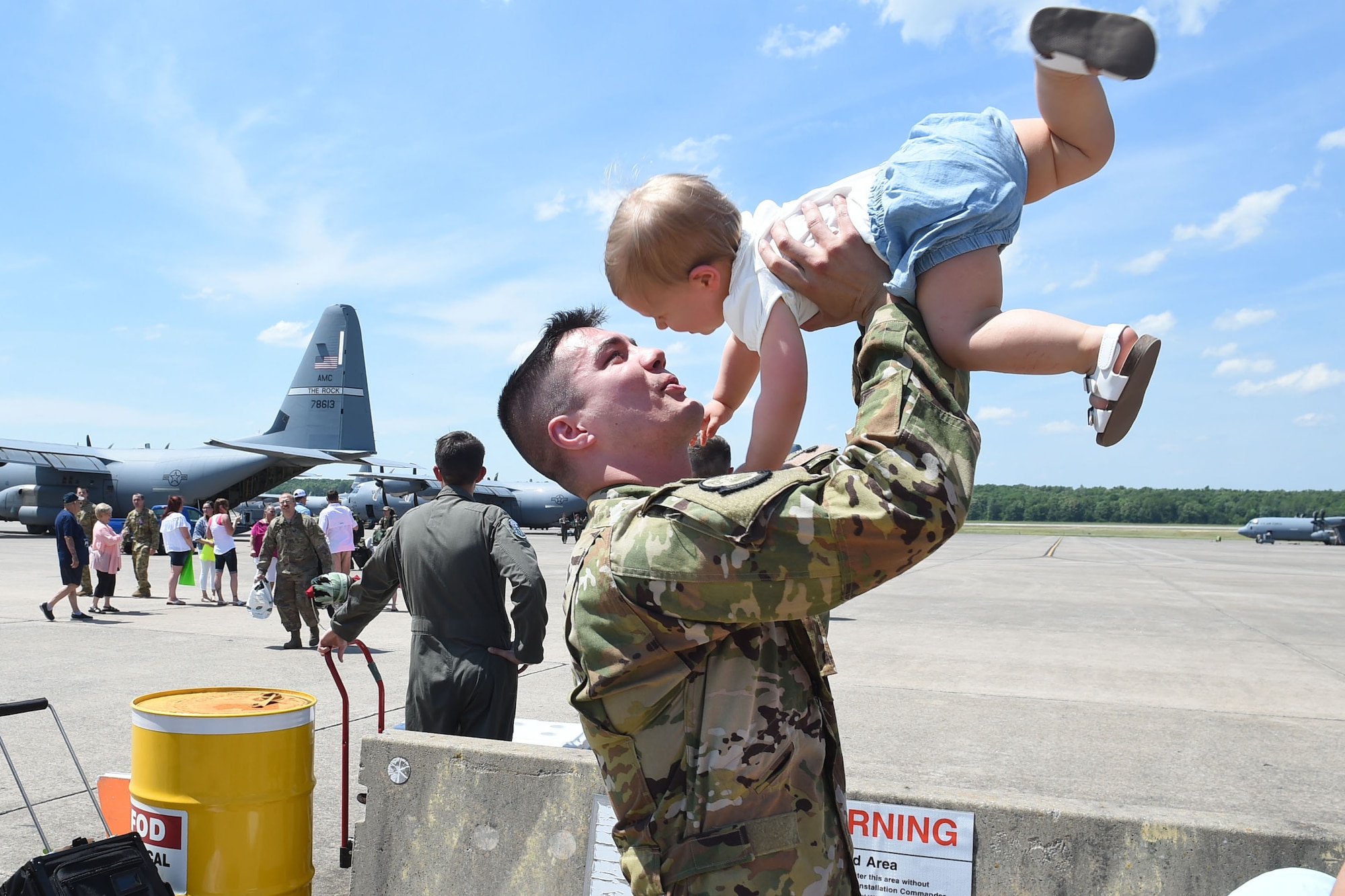 An Airman picks his son up off the ground.