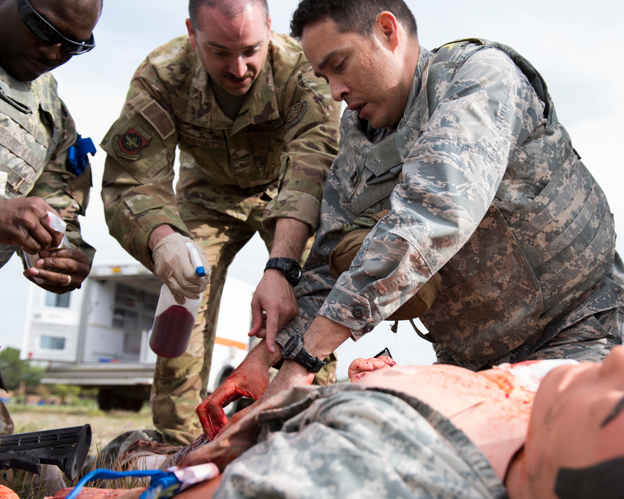 Instructors and students interact over a ‘wounded’ training mannequin during the Tactical Field Care phase of the Tactical Combat Casualty Care course at Fairchild Air Force Base, Washington, Sept. 12, 2019. In a continued effort to save lives, the U.S. Air Force Surgeon General has mandated that all personnel quickly become TCCC certified. (U.S. Air Force photo by Senior Airman Ryan Lackey)