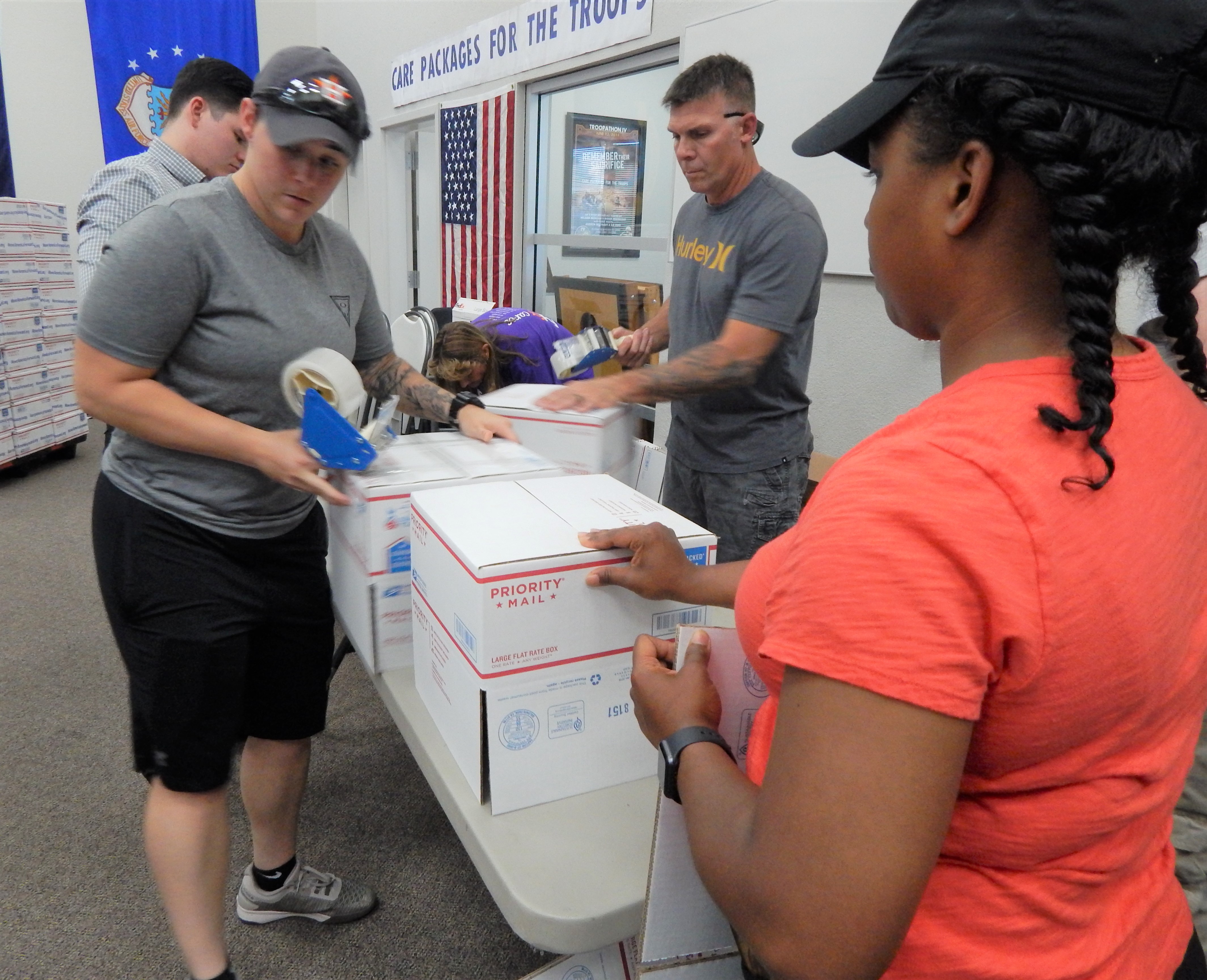 More volunteers tape and secure the United States Post Office shipping boxes before they go out.