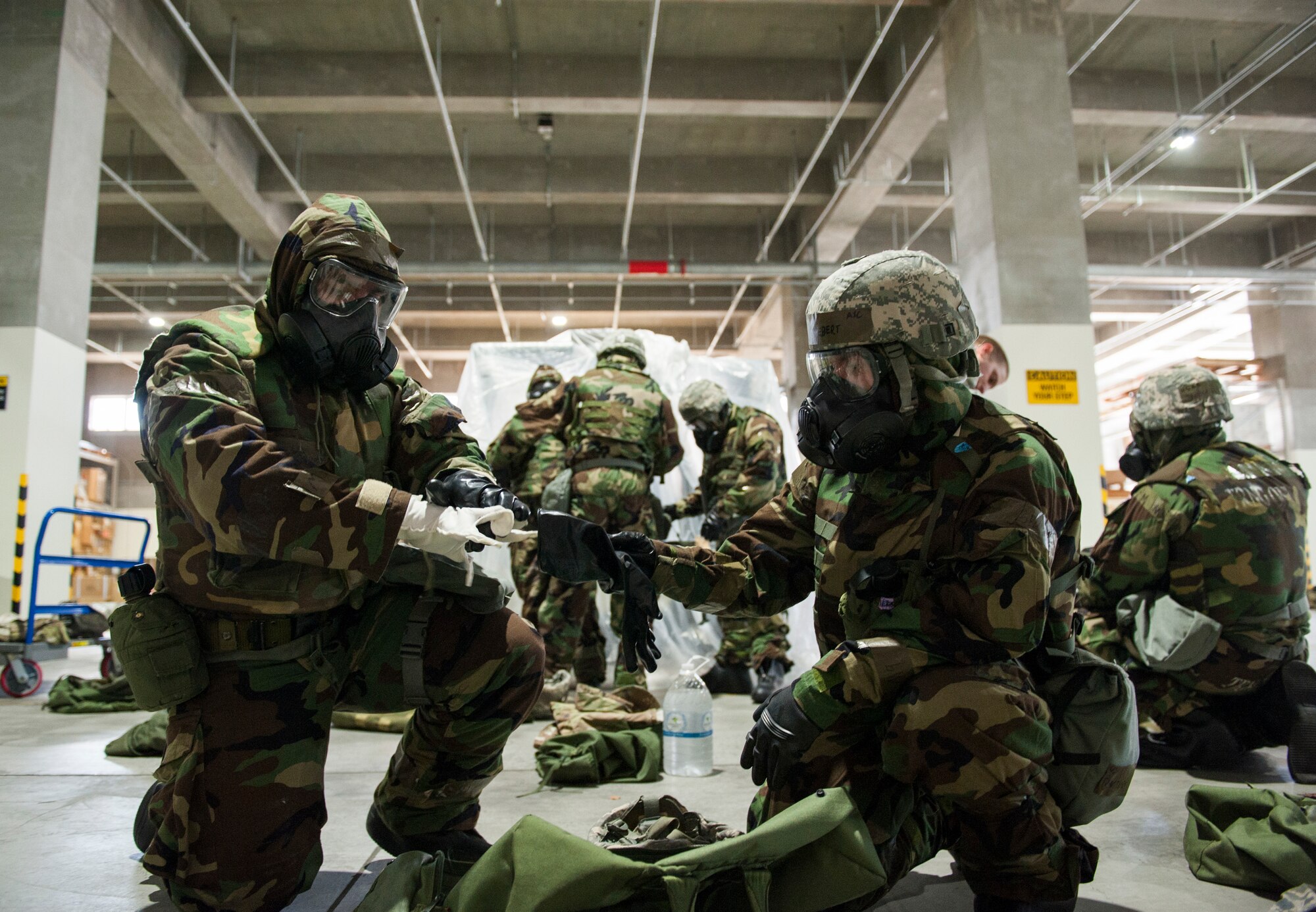 Airmen don protective gloves while putting on Mission-Oriented Protective Posture gear during Ability to Survive and Operate training at Kadena Air Base, Japan, Sept. 12, 2019. The ATSO training is designed to improve an Airman's ability to perform duties in the protective gear. (U.S. Air Force photo by Naoto Anazawa)