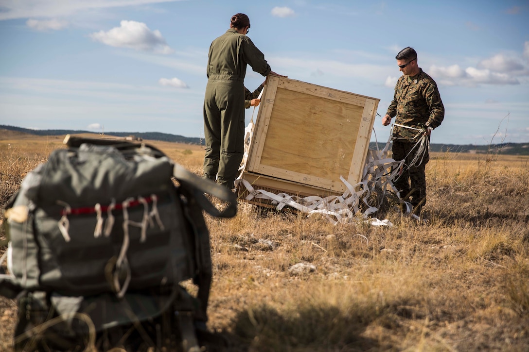 A U.S. Marine and Sailor with Special Purpose Marine Air-Ground Task Force-Crisis Response-Africa 19.2, Marine Forces Europe and Africa, recover a cargo bundle that was dropped from a U.S. Marine Corps KC-130J during a Joint Precision Air Delivery System exercise in Zaragoza, Spain, Aug. 20, 2019. The delivery system is an airdrop device that uses prepared geographic coordinates programmed into a computer system to guide the parachute to the ground. SPMAGTF-CR-AF is deployed to conduct crisis-response and theater-security operations in Africa and promote regional stability by conducting military-to-military training exercises throughout Europe and Africa. (U.S. Marine Corps photo by Cpl. Margaret Gale)
