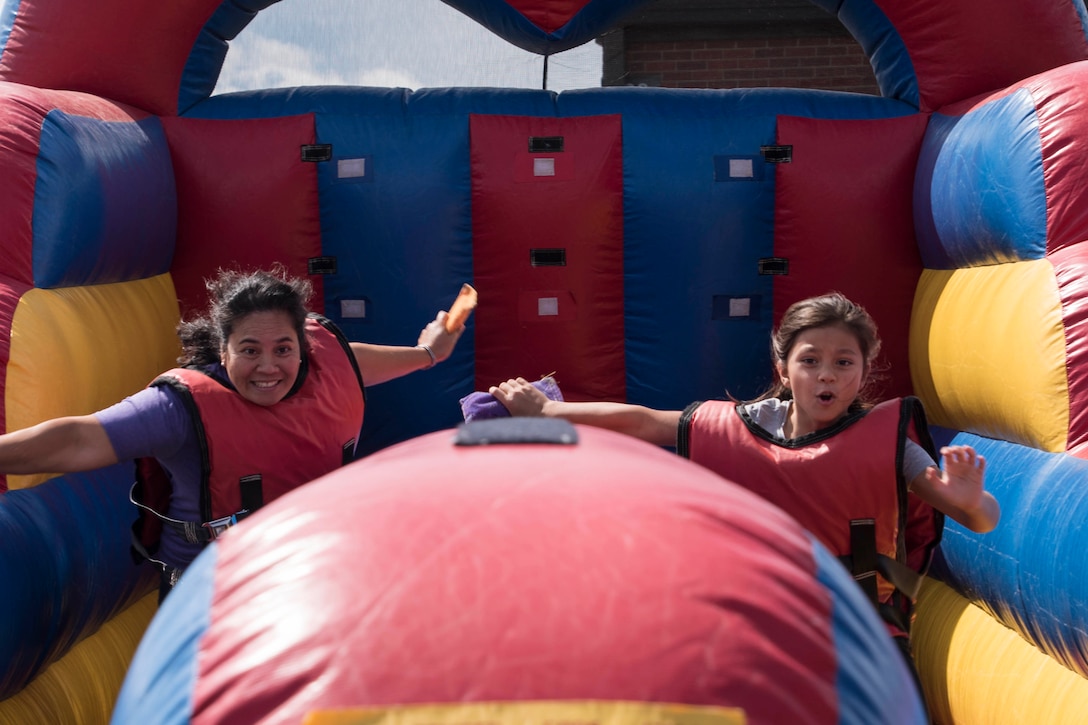Two kids smile as they enjoy an activity at a fair.
