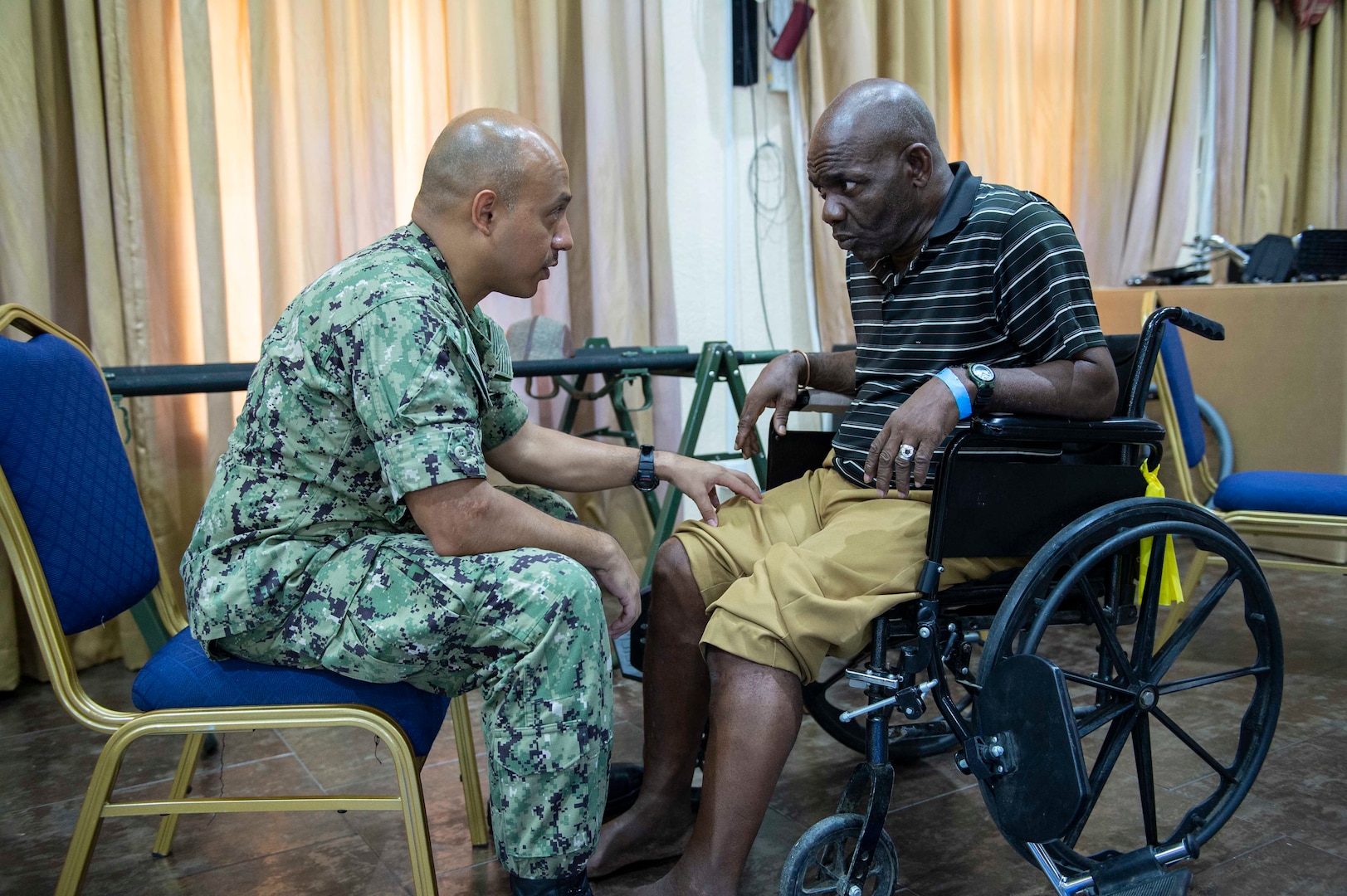 A physical therapist examines a Grenadian man's legs