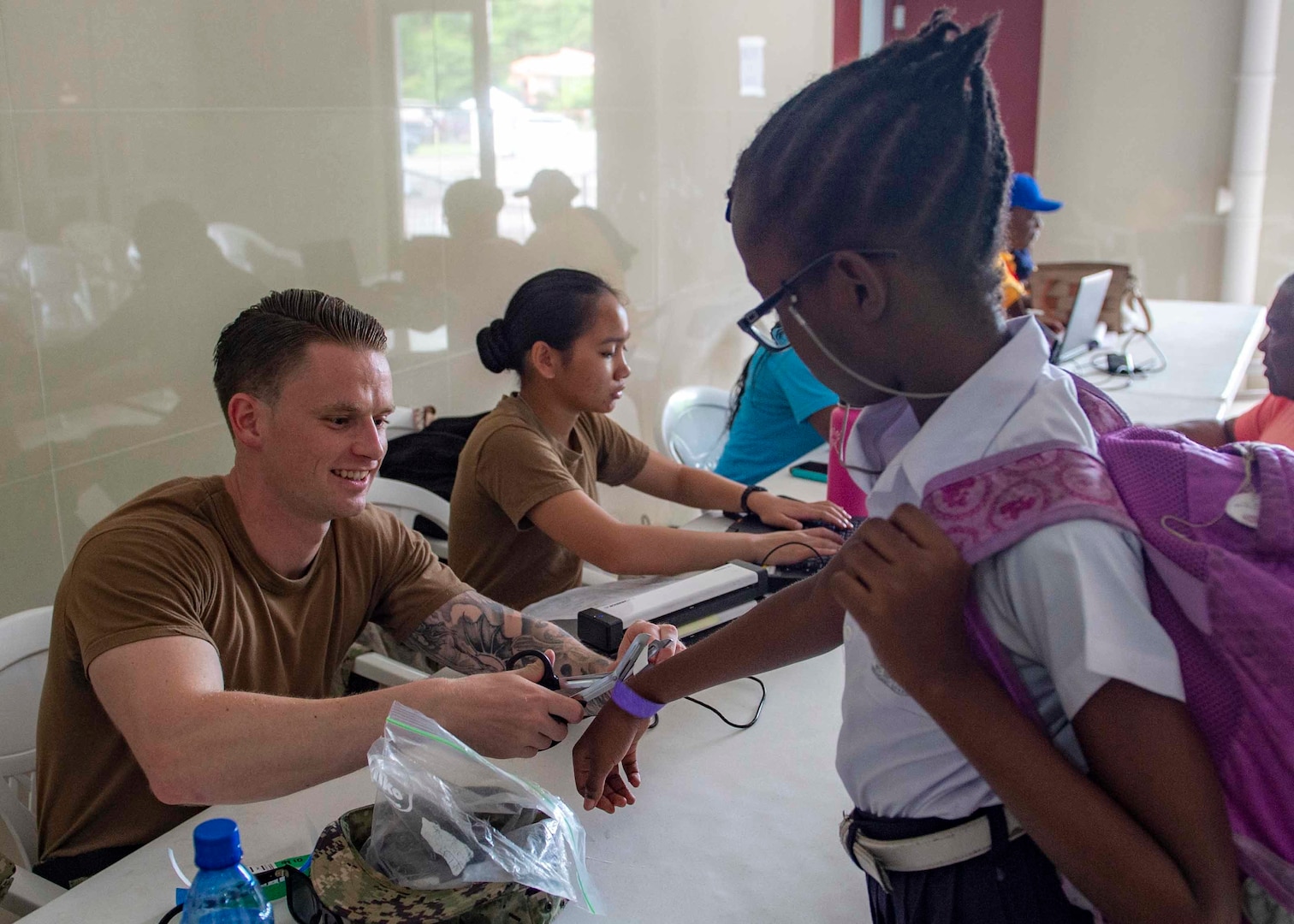 A Sailor removes a Grenadian girl’s bracelet.