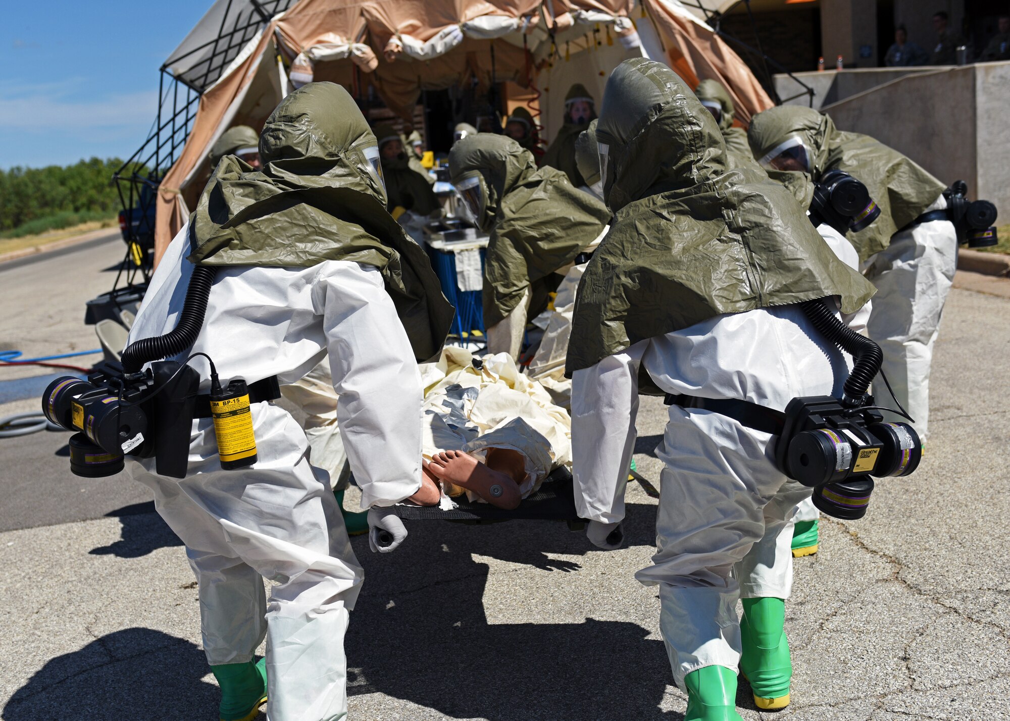 Personnel from the 17th Medical Group carry a simulated patient into the decontamination center during their medical in-place decontamination training at the Ross Clinic on Goodfellow Air Force Base, Texas, September 12, 2019. This training includes many different aspects such as setting up the decontamination center along with decontaminating and treating patients. (U.S. Air Force photo by Airman 1st Class Robyn Hunsinger/Released)