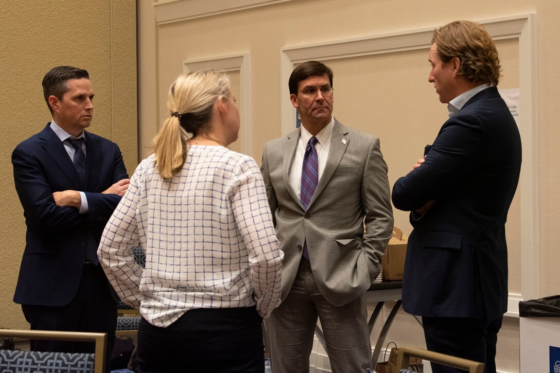 Three men in suits and a woman stand in a circle talking.