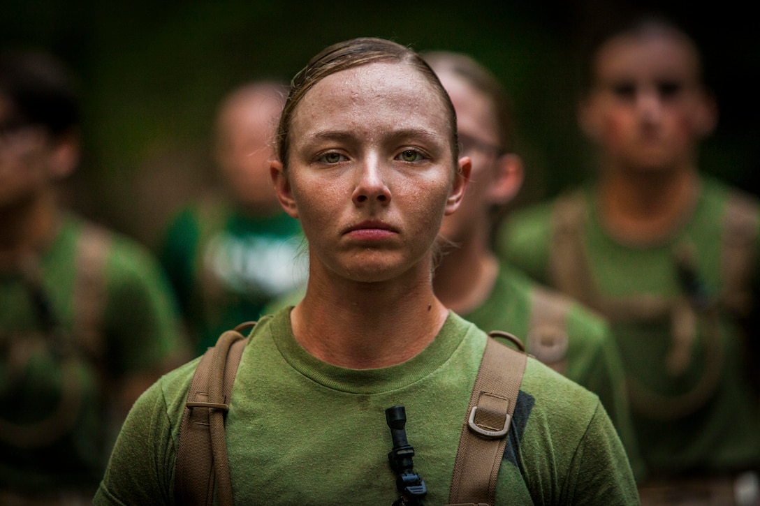 A Marine surrounded by other Marines looks at the camera.