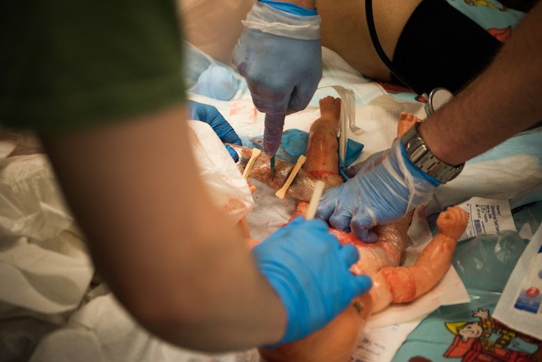 Medics from Royal Air Force Lakenheath, England, cut the umbilical cord of a replica baby during an on-scene birth scenario at the 2019 Medic Rodeo at Cannon Air Force Base, N.M., Sept. 18, 2019. The Medic Rodeo is designed to test the skills of air force medical technicians in both deployed and home installation environments. (U.S. Air Force photo by Staff Sgt. Michael Washburn)