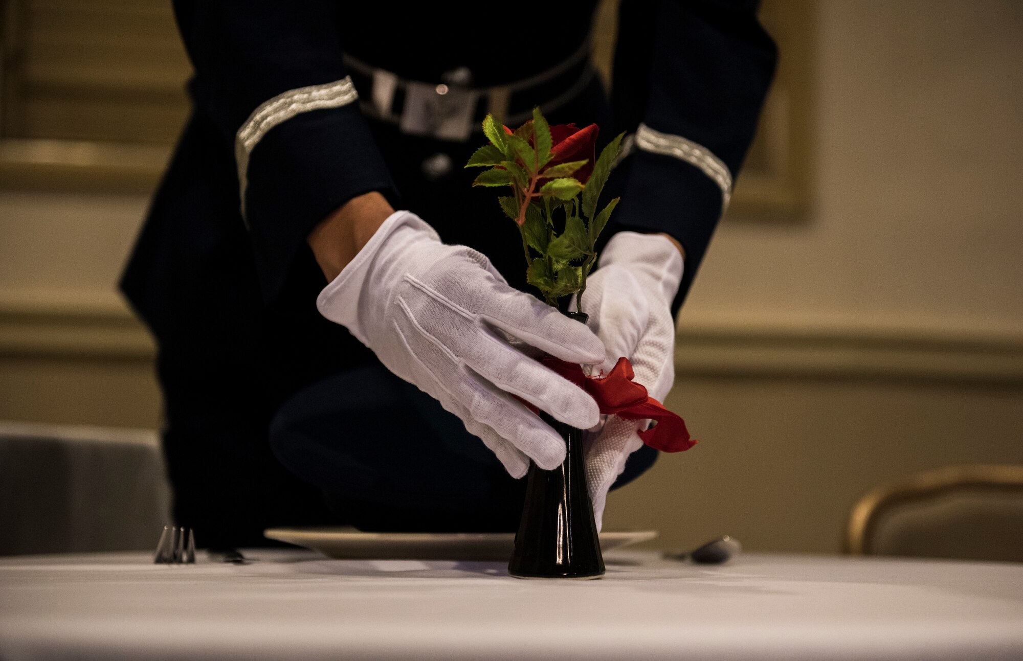 A member of the 8th Fighter Wing base honor guard places a red flower on the prisoners of war and missing in action table during a memorial ceremony at Kunsan Air Base, Republic of Korea, Sept. 20, 2019. The Wolf Pack dedicated the week in honor of POW/MIA that consisted of several events for the base to participate in, such as a 10 kilometer ruck march, a memorial run and a candle light vigil. (U.S. Air Force photo by Senior Airman Stefan Alvarez)