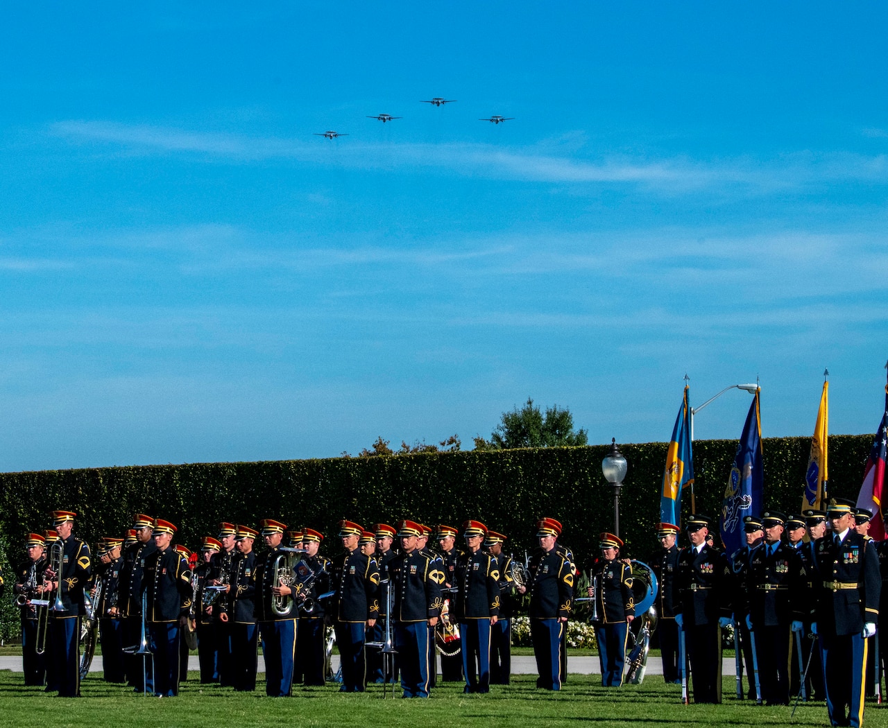 Military aircraft fly over a joint service color guard.