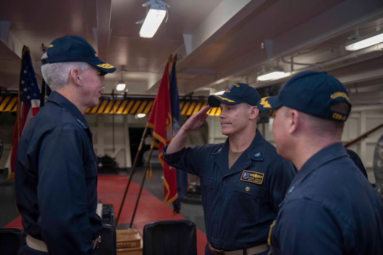 PHILIPPINE SEA (Sept. 20, 2019) Rear Adm. Karl Thomas, commander, Task Force 70, far left, Capt. Steve DeMoss, commander, Destroyer Squadron 15, center, and Cmdr. Jennifer Bowden, USS Ronald Reagan chaplain, salute during a Destroyer Squadron (DESRON) 15 change of command ceremony aboard the forward-deployed aircraft carrier USS Ronald Reagan (CVN 76). DESRON 15 is the Navy's largest forward-deployed DESRON and the U.S. 7th Fleet's principal surface force.