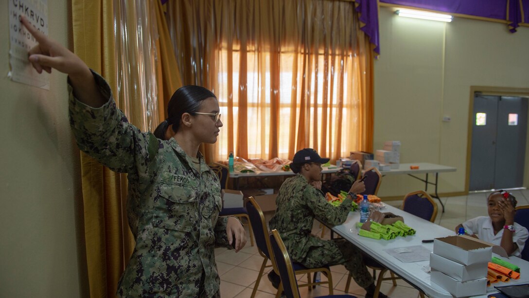 A Navy Hospitalman conducts a sight test on a Grenadian child.