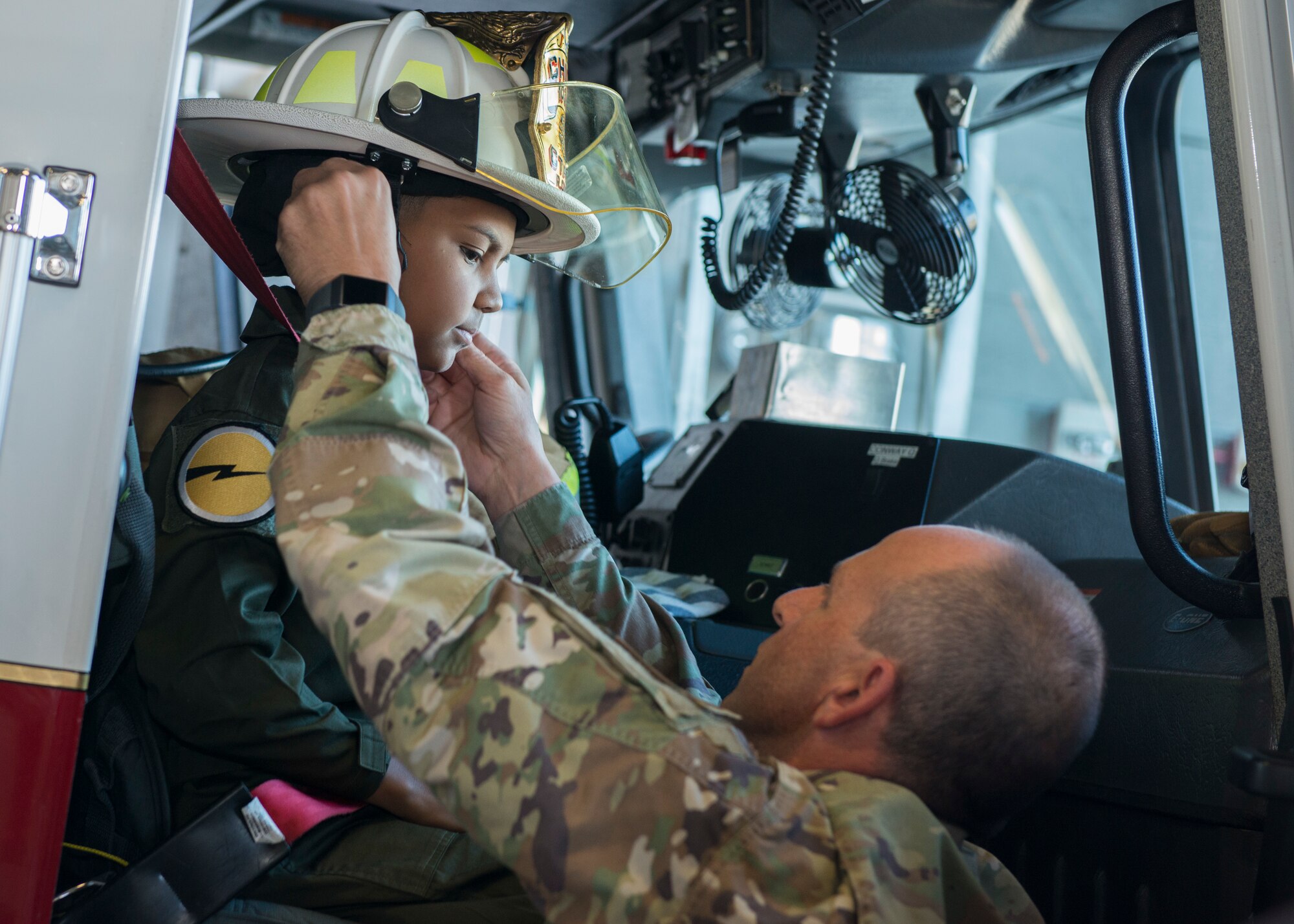 Chief Master Sgt. Robert Cross, 103rd Civil Engineer Squadron fire chief, fits his helmet on Jadiel Aponte, 103rd Airlift Wing honorary Pilot for a Day, during the wing’s annual Pilot for a Day event at Bradley Air National Guard Base, East Granby, Conn. Sept. 19, 2019. The program puts the wing in partnership with local hospitals to identify a child with a life-threatening or terminal illness and bring them on base to meet members of the wing and learn about its mission. (U.S. Air National Guard photo by Staff Sgt. Steven Tucker)