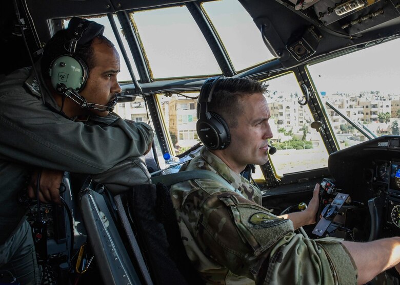 A member of the Royal Jordanian Air Force looks over the shoulder of Capt. Anthony Toste, a 700th Airlift Squadron pilot, during the familiarity flight in Jordan during Exercise Eager Lion on Aug. 25, 2019.