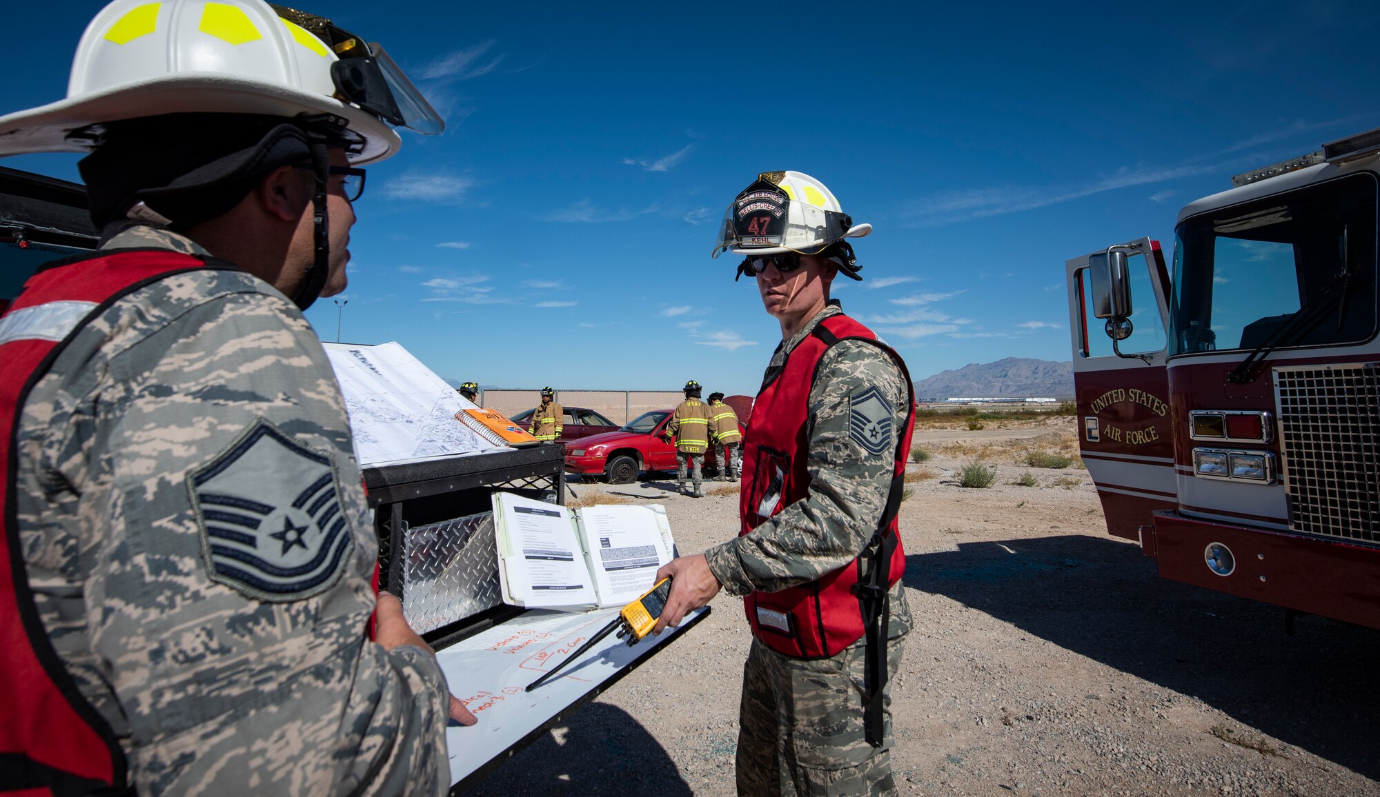 Two Air Force fire fighters review a manual.