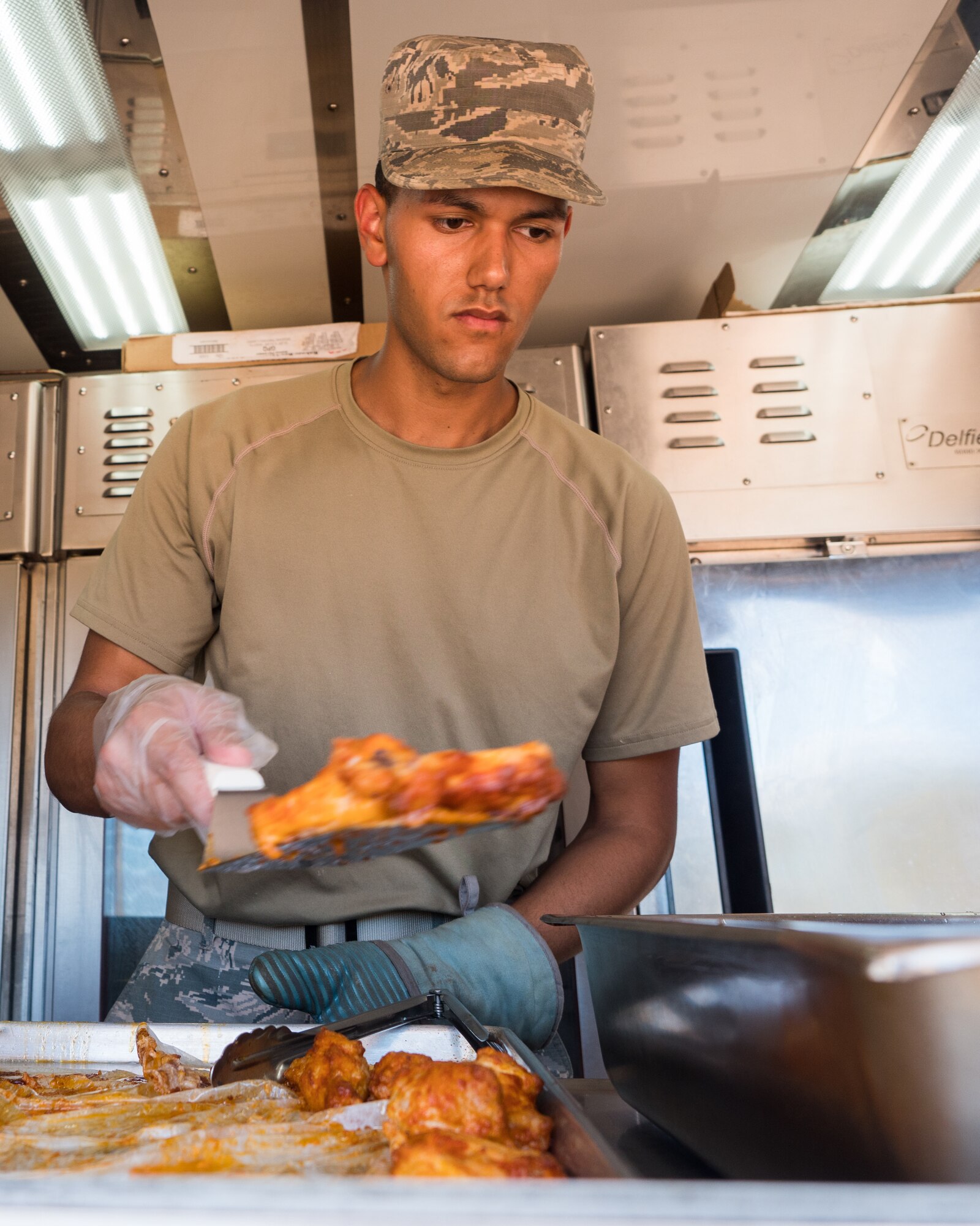 U.S. Air Force Senior Airman Ernesto Lopez Falcon, a services specialist with the 116th Air Control Wing (ACW), Georgia Air National Guard, prepares chicken wings for lunch from a Disaster Relief Mobile Kitchen Trailer during Innovative Readiness Training at Camp Paumalu Girl Scout Camp, Hawaii, July 24, 2019.