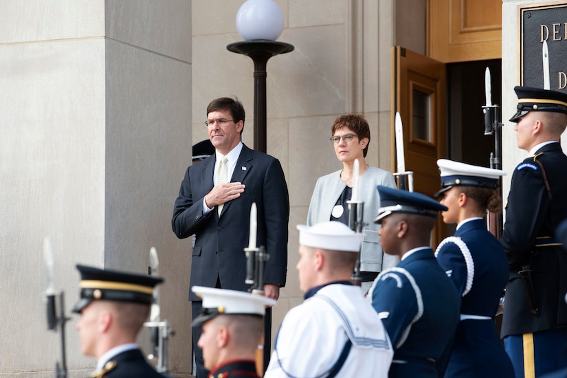 Two defense leaders stand in front of an entrance to the Pentagon.