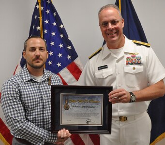 IMAGE: DAHLGREN, Va. (Aug. 30, 2019) – Naval Sea Systems Warfare Centers Commander Rear Adm. Eric Ver Hage presents the Secretary of Defense Medal for the Global War on Terrorism (GWOT) plaque to Nicholas Mastrokalos at an award ceremony moments after pinning the medal on Mastrokalos – a Naval Surface Warfare Center Dahlgren Division (NSWCDD) engineer. The GWOT Medal recognized and honored Mastrokalos’ contributions and accomplishments in direct support of the armed forces engaged in operations to combat terrorism.