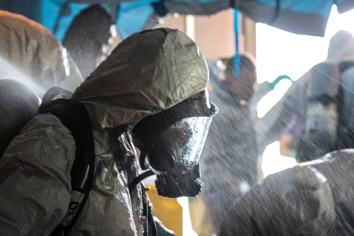 U.S. Marine Corps Lance Cpl. Kimberly Ortiz Marrero, a native of Lancaster, N.Y. and the hazardous material and safety representative for 3rd Transportation Support Battalion, stands while being decontaminated during the Hazardous Waste Operations and Emergency Response course at Camp Foster, Okinawa, Japan, Sept. 19, 2019. After completing an exercise, all the students who wore hazardous material suits had to undergo a mock-decontamination procedure where they entered a tent and were sprayed with water.