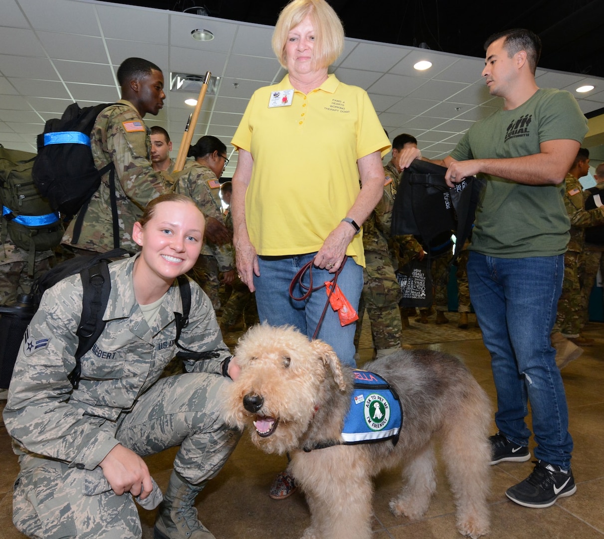 An Airman poses for a photo with a working therapy dog brought by volunteers with Paws 4 Hearts.