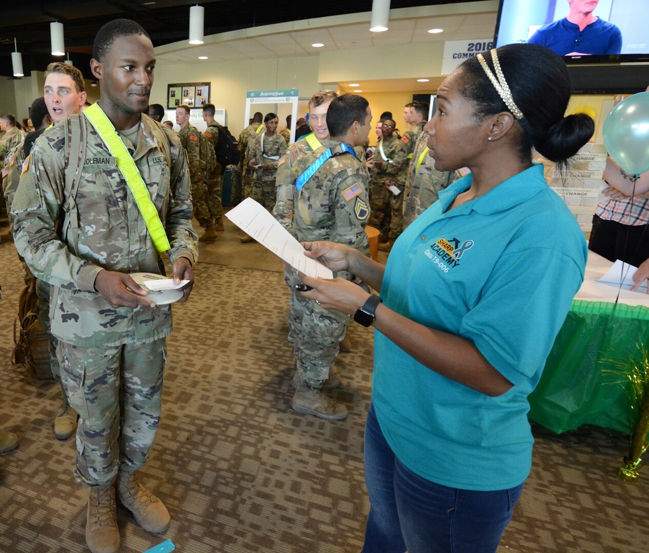 A We Care Carnival volunteer hands a Soldier a prize at the Frisbee booth.