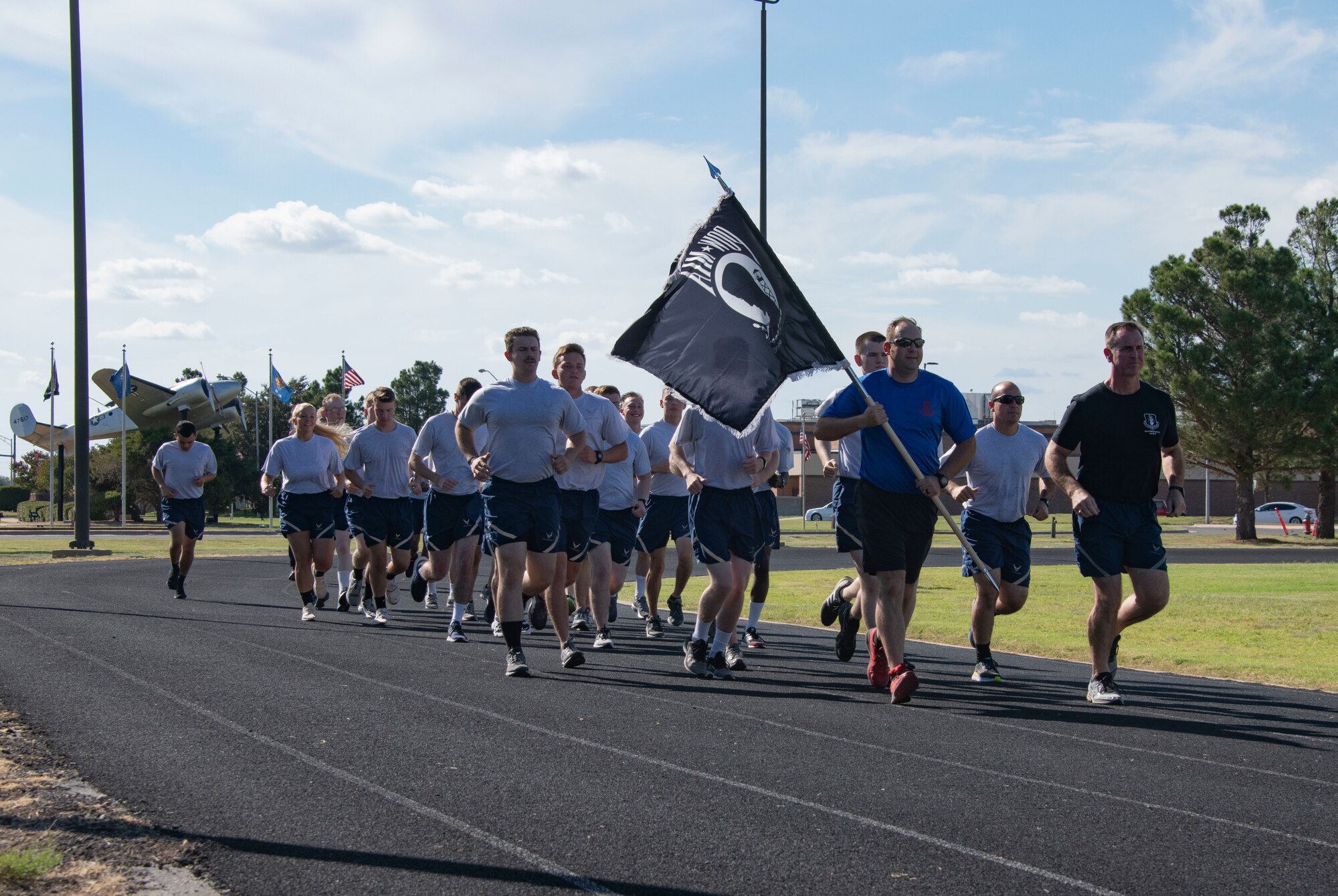 U.S. Air Force Tech. Sgt. Matthew Songe, Military Training Leader assigned to the 97th Training Squadron, holds the POW/MIA flag, joined by Col. William Mickley, 97th Air Mobility Wing vice commander and students of the 97th TRS, during the 24-hour POW/MIA remembrance run