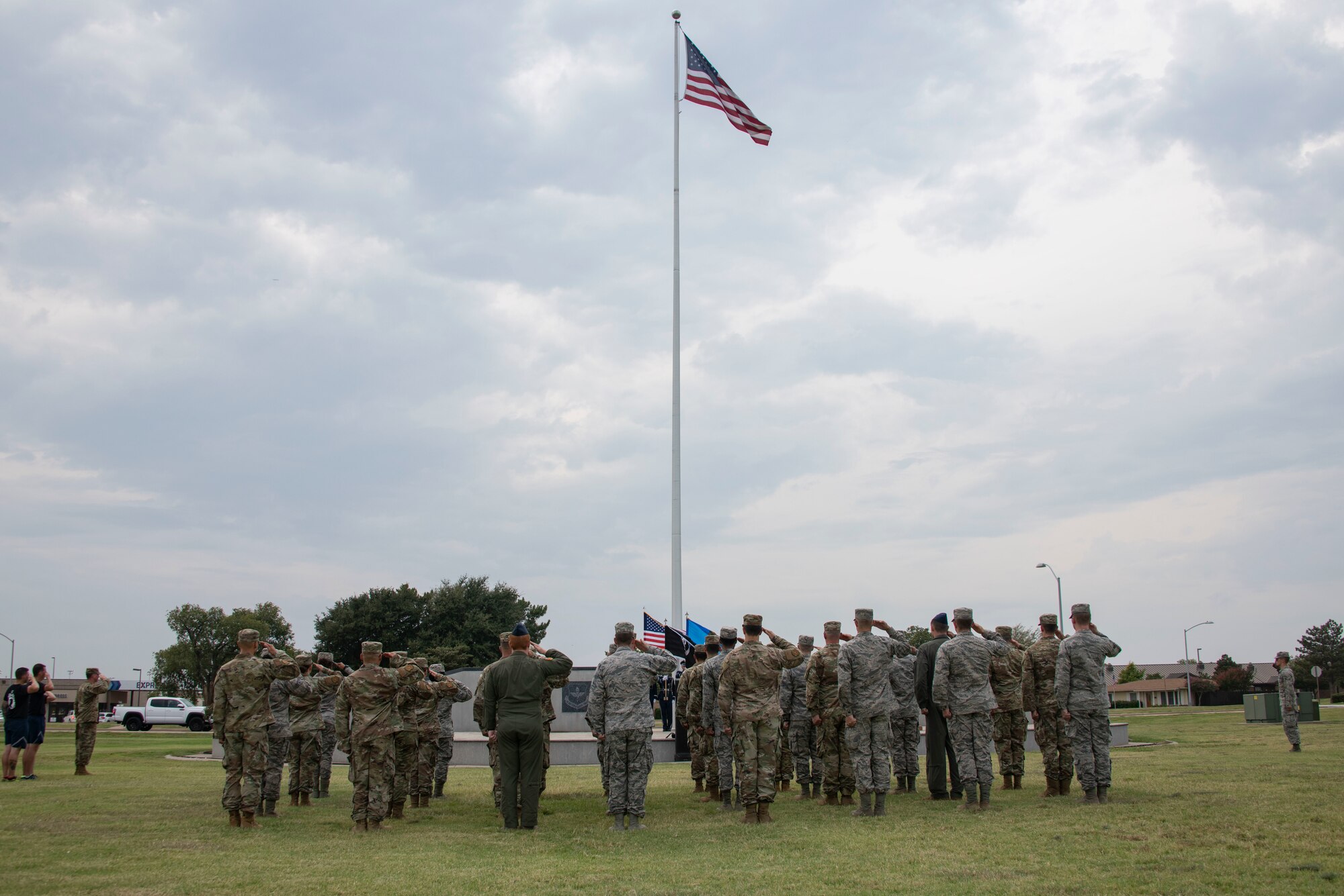 Members of the 97th Air Mobility Wing salute the flag at reveille during the closing ceremony of the POW/MIA Recognition Day