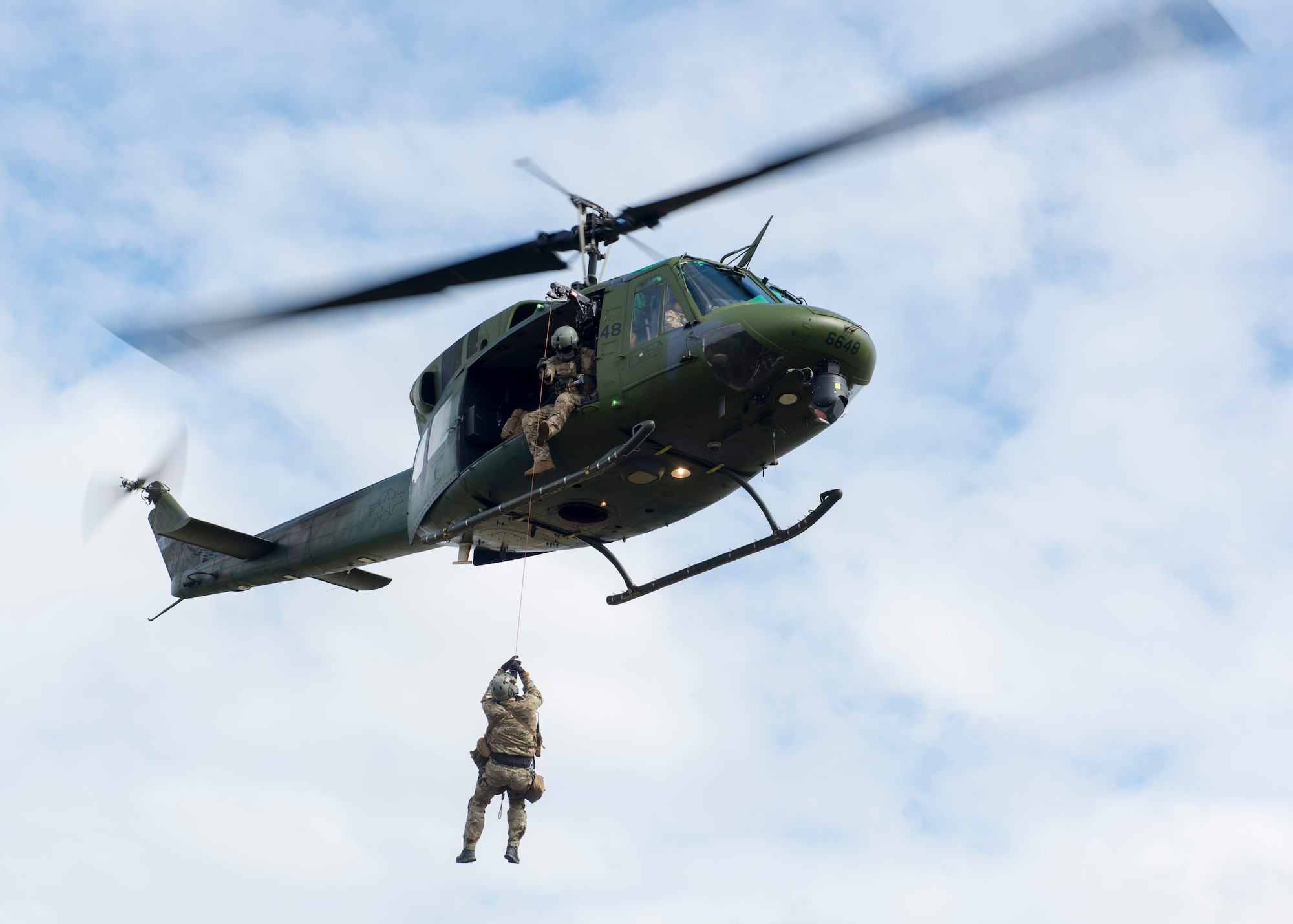 U.S. Air Force Tech. Sgt. Scott Grubaugh, 36th Rescue Squadron flight engineer, hoists up Tech. Sgt. James Pennington, 336th Training Group independent medical technician during a medical evacuation demonstration prior to the commemoration ceremony of the 36th RQS reaching 700 saves at Fairchild Air Force Base, Washington, Sept. 20, 2019. The 36th RQS is the only operational rescue squadron flying UH-1N helicopters within the United States that is qualified to perform 24-hour medical evacuation alert, water rescue, cargo sling and hoist operations. (U.S. Air Force photo by Airman 1st Class Lawrence Sena)