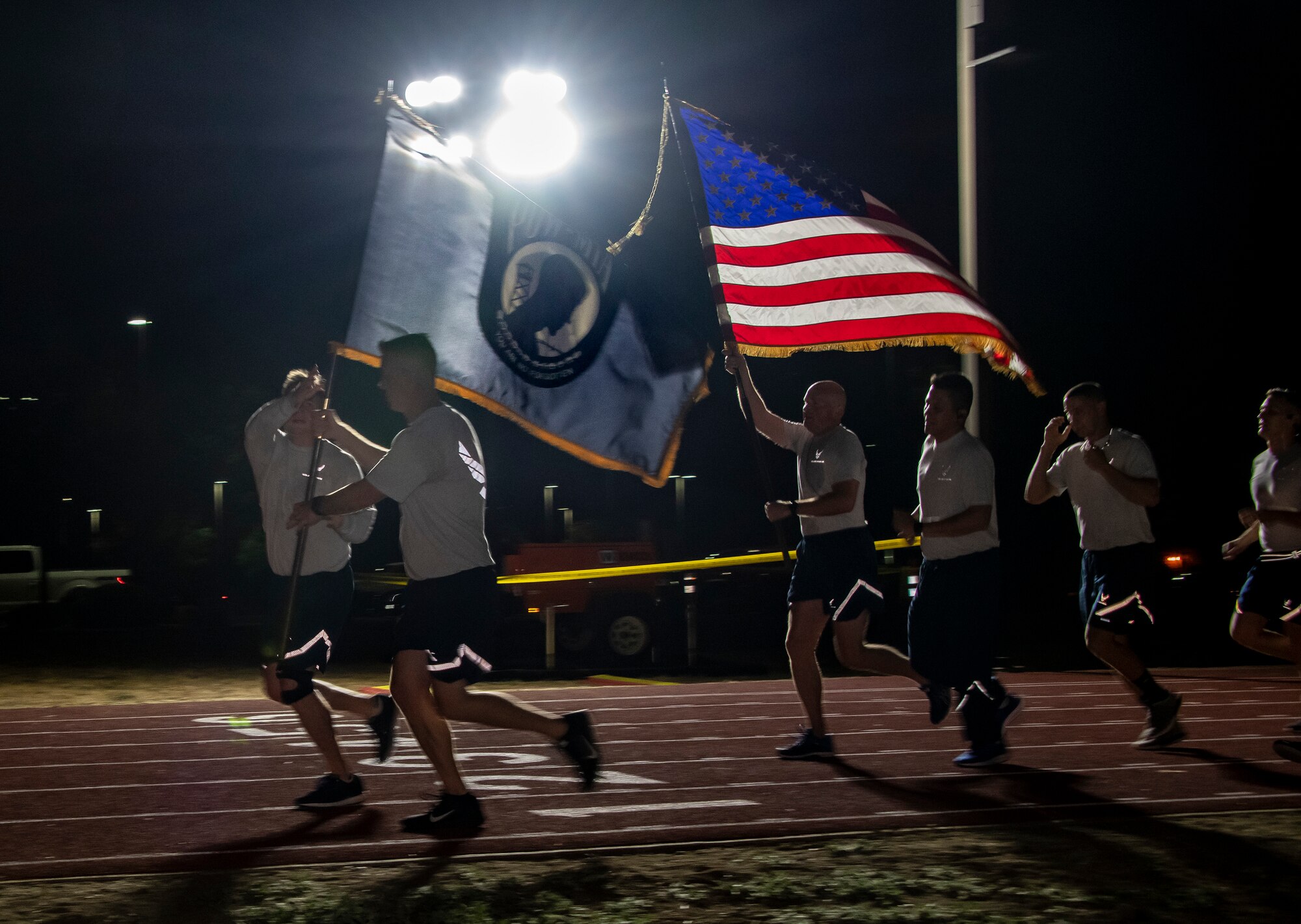 Members of the 860th Aircraft Maintenance Squadron run on the fitness center track with the U.S. and POW/MIA flags Sept. 20, 2019, at Travis Air Force Base, California. Service members, civilians and family members kept the flags in constant motion for a 24-hour period. According to the Defense POW/MIA Accounting Agency, more than 82,000 Americans remain missing from WWII, Korean War, Vietnam War, Cold War, Gulf Wars and other conflicts. The names of service members still unaccounted for were recited throughout the run. (U.S. Air Force photo by Heide Couch)