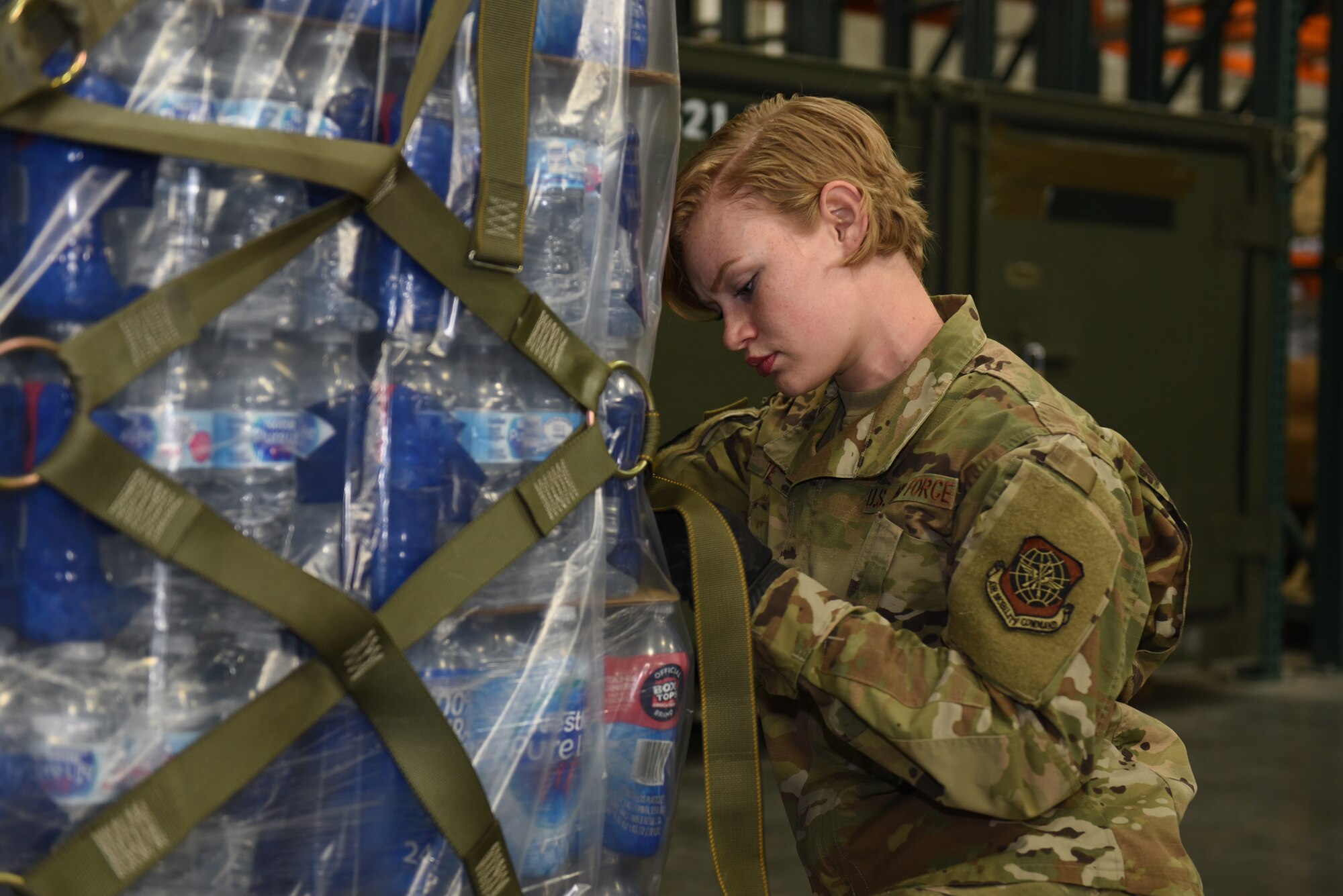 U.S. Air Force Airman 1st Class Marley White, 821st Contingency Response Support Squadron air transportation specialist, fastens straps on a pallet of supplies for a Mobility Guardian 2019 deployment Sept. 12, 2019, at Travis Air Force Base, California. MG19 is Air Mobility Command’s flagship exercise for large-scale rapid global mobility operations. Travis AFB is serving as a staging base for the exercise, which is taking place at Fairchild AFB, Washington. (U.S. Air Force photo by Airman First Class Cameron Otte)