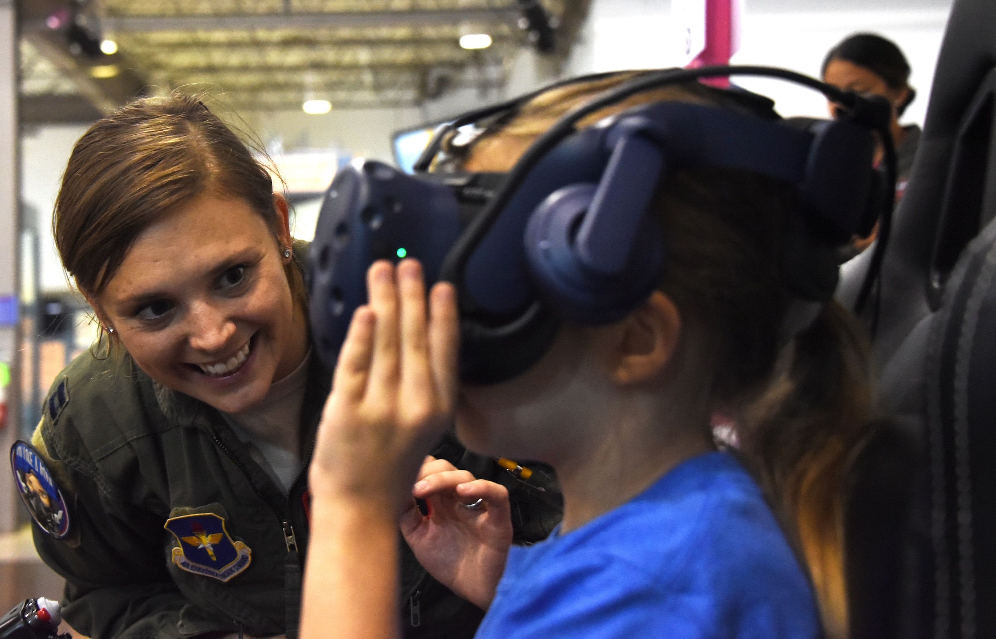 An Air Education and Training Command Women’s Fly-In Event participant guides a young woman through a virtual reality
