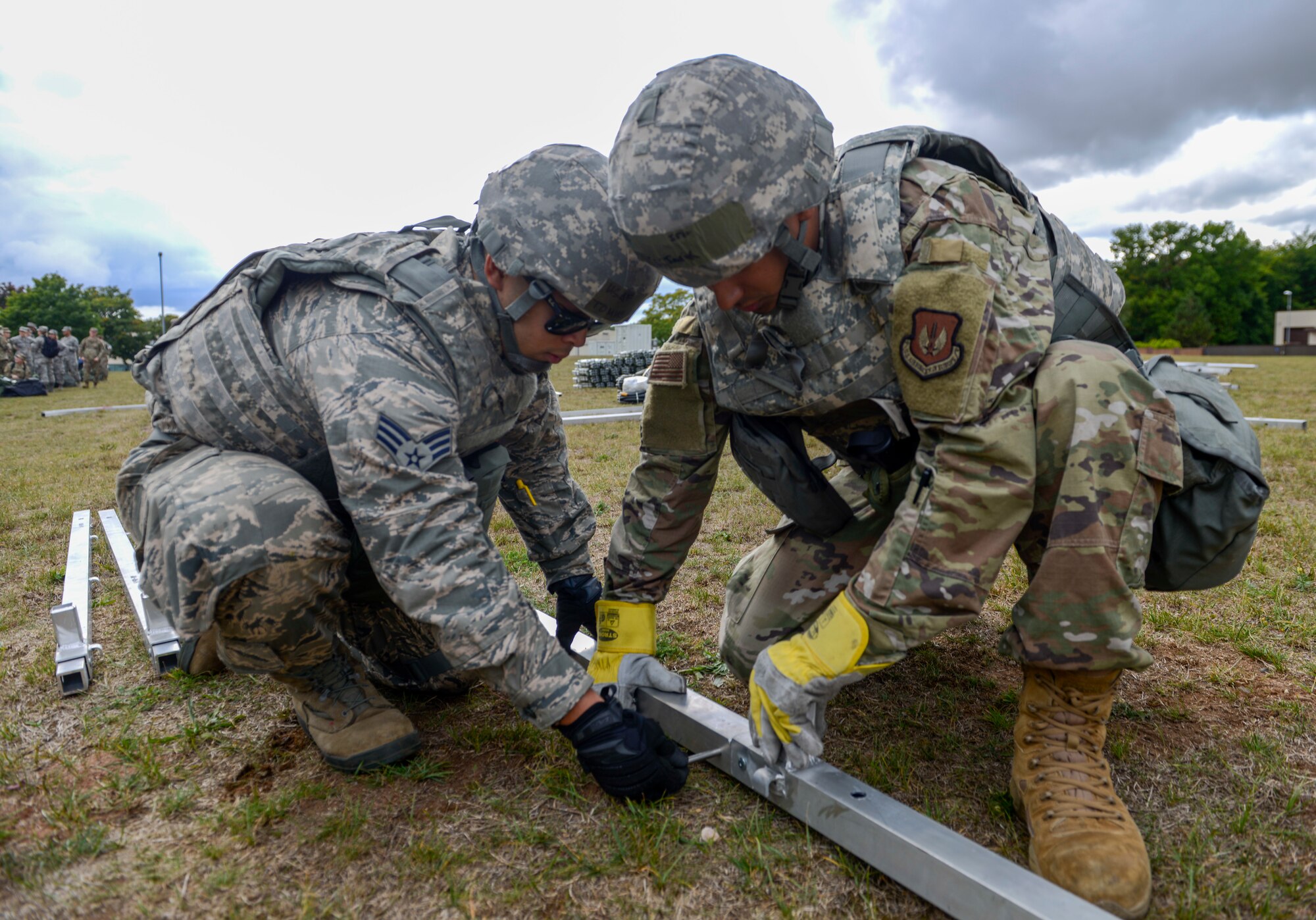 U.S. Air Force Senior Airman Tommy Pestano, left, and Senior Airman Jarik Biggs, both assigned to the 786th Civil Engineer Squadron, build the frame of a tent as part of Operation Varsity 19-3 at Ramstein Air Base, Germany, Sept. 23, 2019. The tents were used as temporary lodging for simulated deployers during Operation Varsity 19-3, a weeklong exercise designed to test the capabilities of Ramstein Airmen. (U.S. Air Force photo by Tech. Sgt. Timothy Moore)