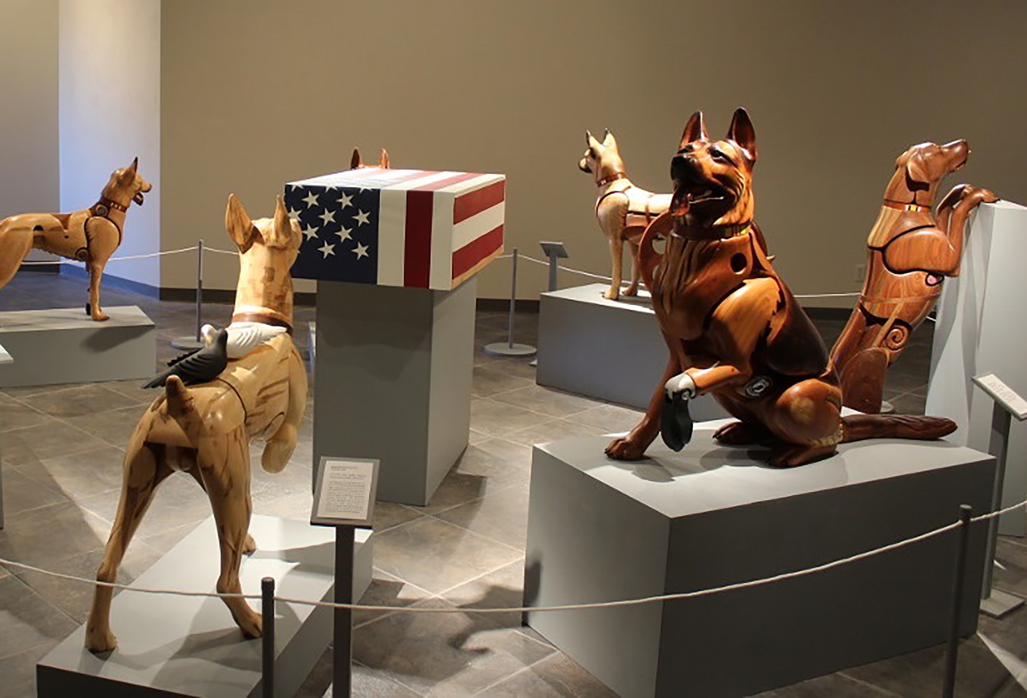 Picture showing wooden sculpture dogs on display as an exhibit.