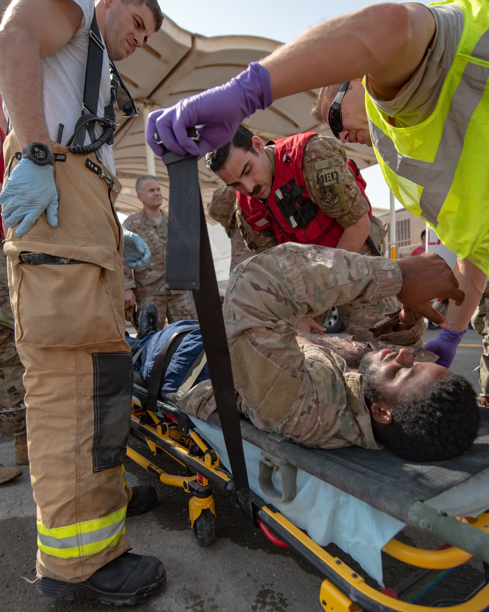 380th Air Expeditionary Wing firefighters and medics secure a moulage victim to a gurney during a large first responder exercise Sept. 24, 2019, at Al Dhafra Air Base, United Arab Emirates. A variety of agencies including medics, firefighters and security forces defenders participated in the exercise to test their readiness, knowledge of emergency procedures and interagency cooperation amongst the wing’s first responders. (U.S. Air Force photo by Staff Sgt. Chris Thornbury)