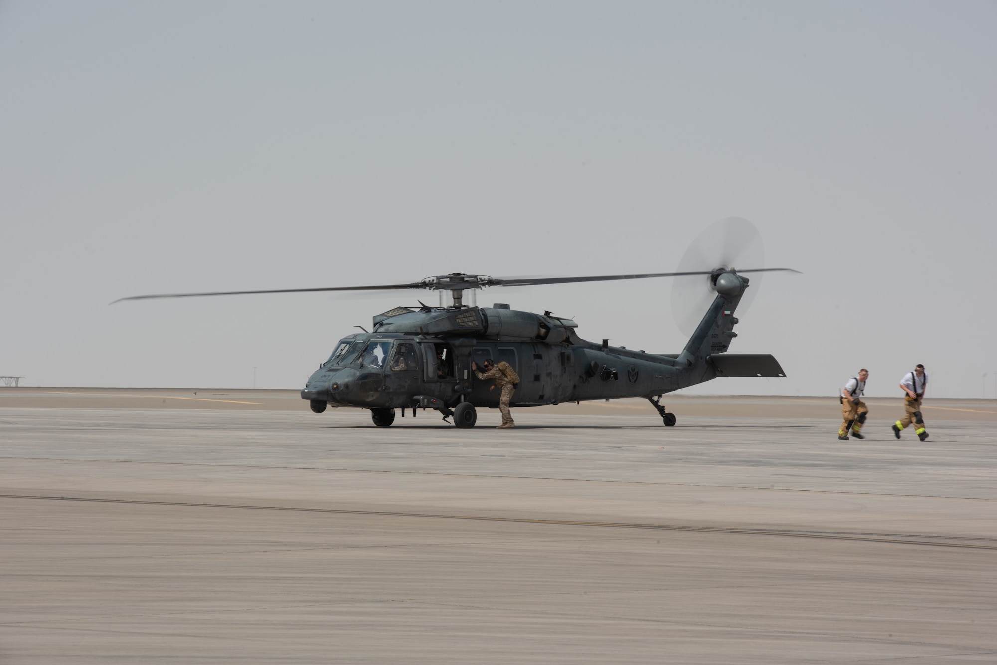 380th Air Expeditionary Wing firefighters back away from an Emirati UH-60 Black Hawk after handing off a simulated patient during a large first responder exercise Sept. 24, 2019, at Al Dhafra Air Base, United Arab Emirates. The exercise helped foster partnership with the United Arab Emirates Air Force Joint Aviation Command to practice an aeromedical evacuation scenario via helicopter. (U.S. Air Force photo by Staff Sgt. Chris Thornbury)