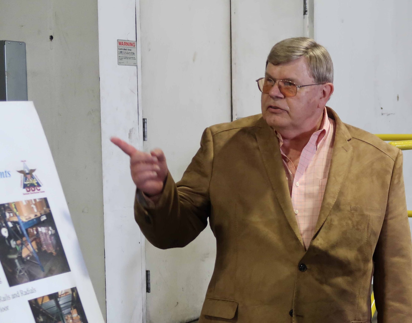 Defense Logistics Agency Oklahoma City, Oklahoma, Director, Ned LaViolette points to a posterboard during a tour of DDOO.